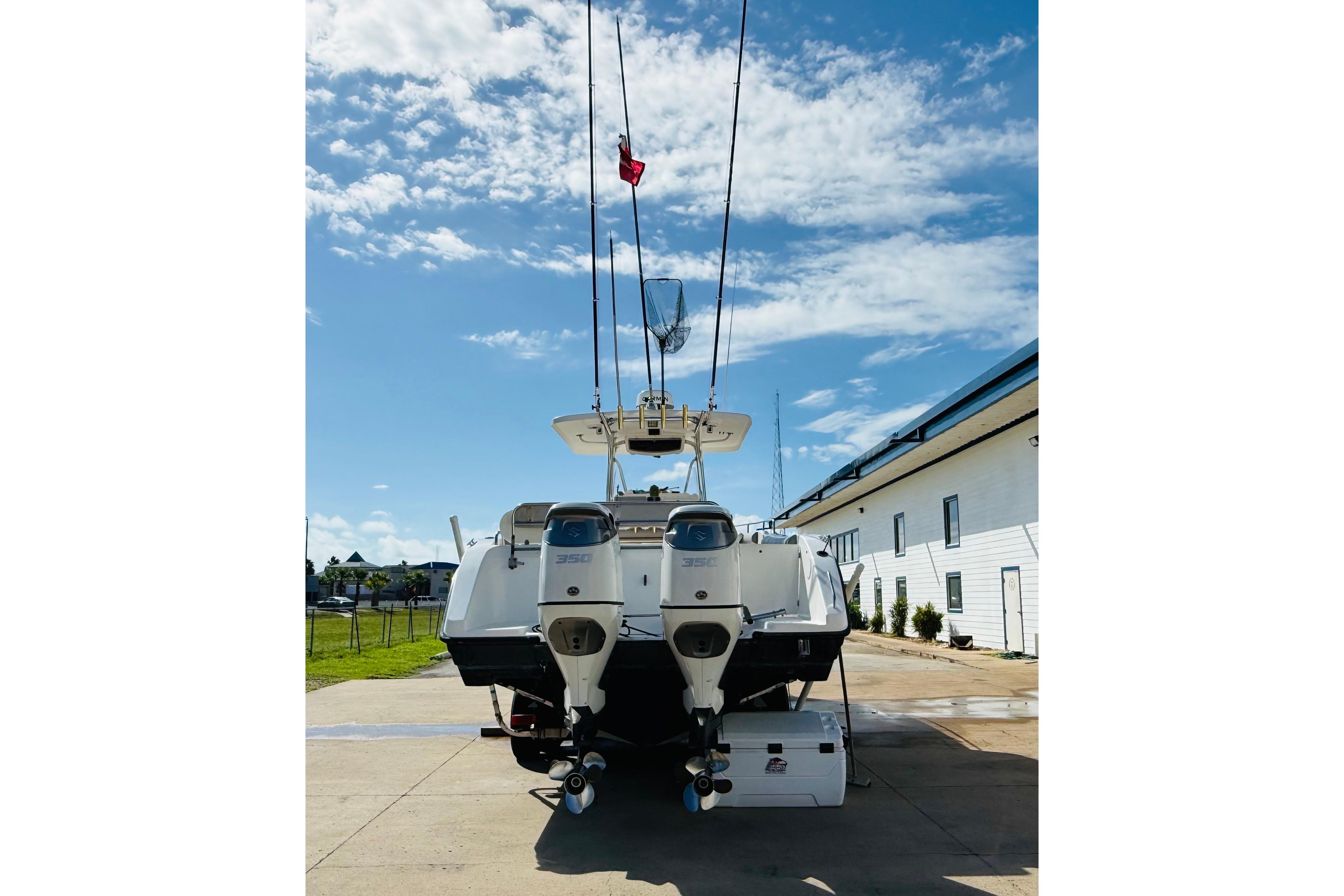 2005 Century 3200 Center Console boat with dual engines, docked under a clear blue sky.