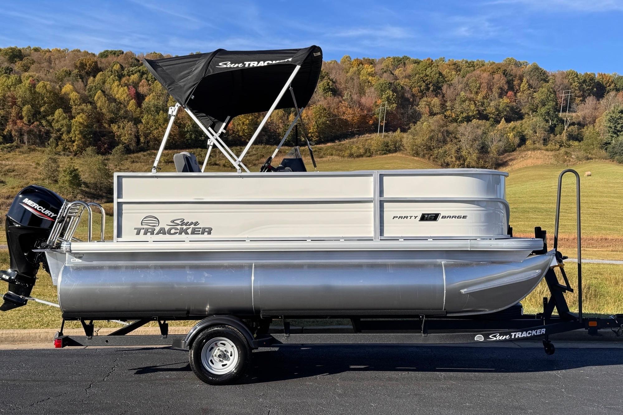 2026 Sun Tracker Party Barge 16 DLX pontoon boat on trailer, scenic background.