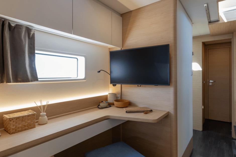 Modern interior of 2026 Fountaine Pajot 44 yacht with desk, TV, and window.