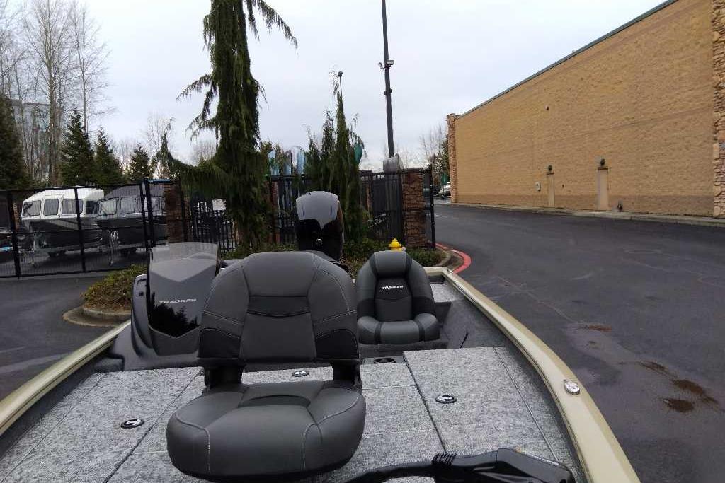 2026 Tracker Pro Team 195 boat with gray seating, parked near a building.