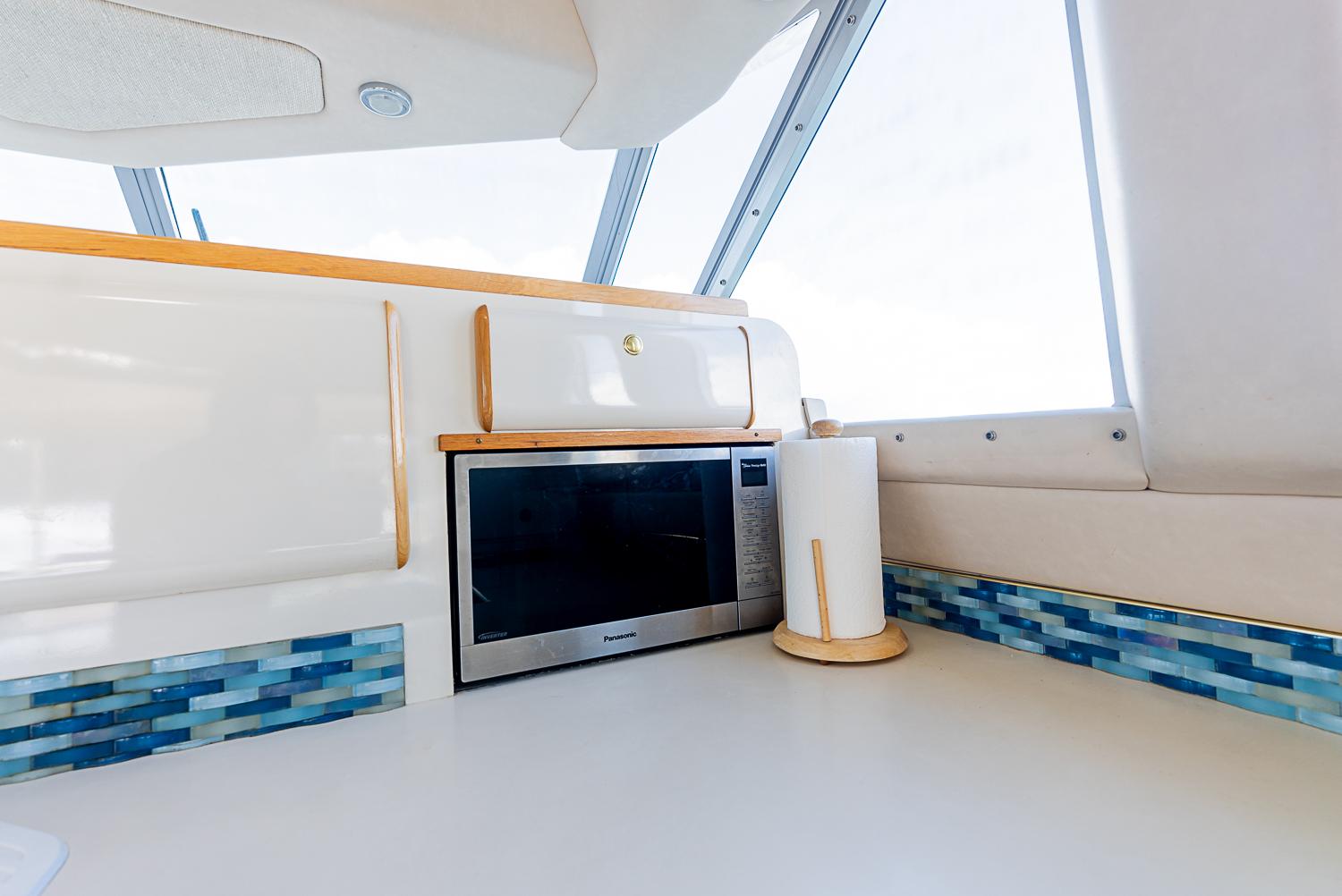 Interior of 1995 Sea Ray Sedan Bridge with microwave and modern blue tile accents.