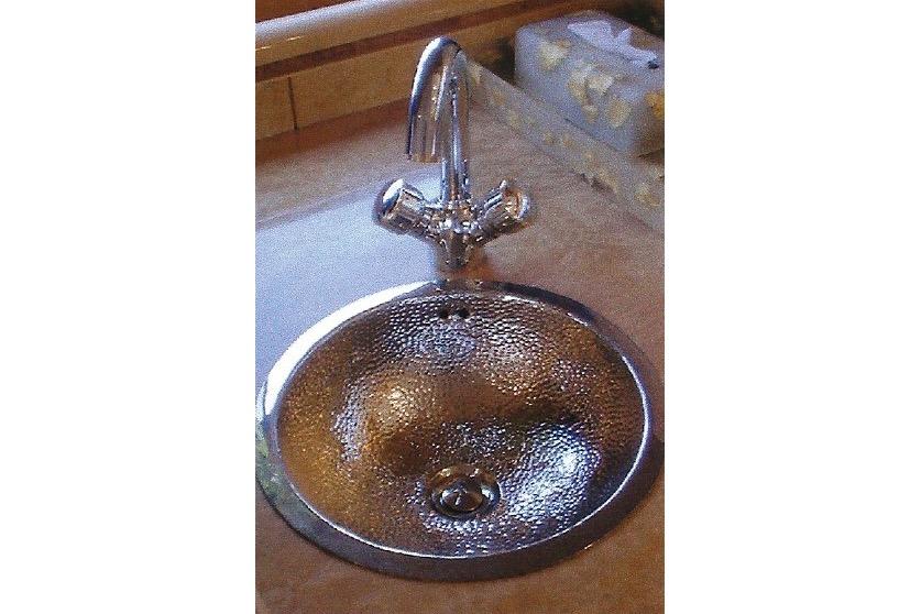 Hammered metal sink with chrome faucet on a countertop, Dyna Laguna model.