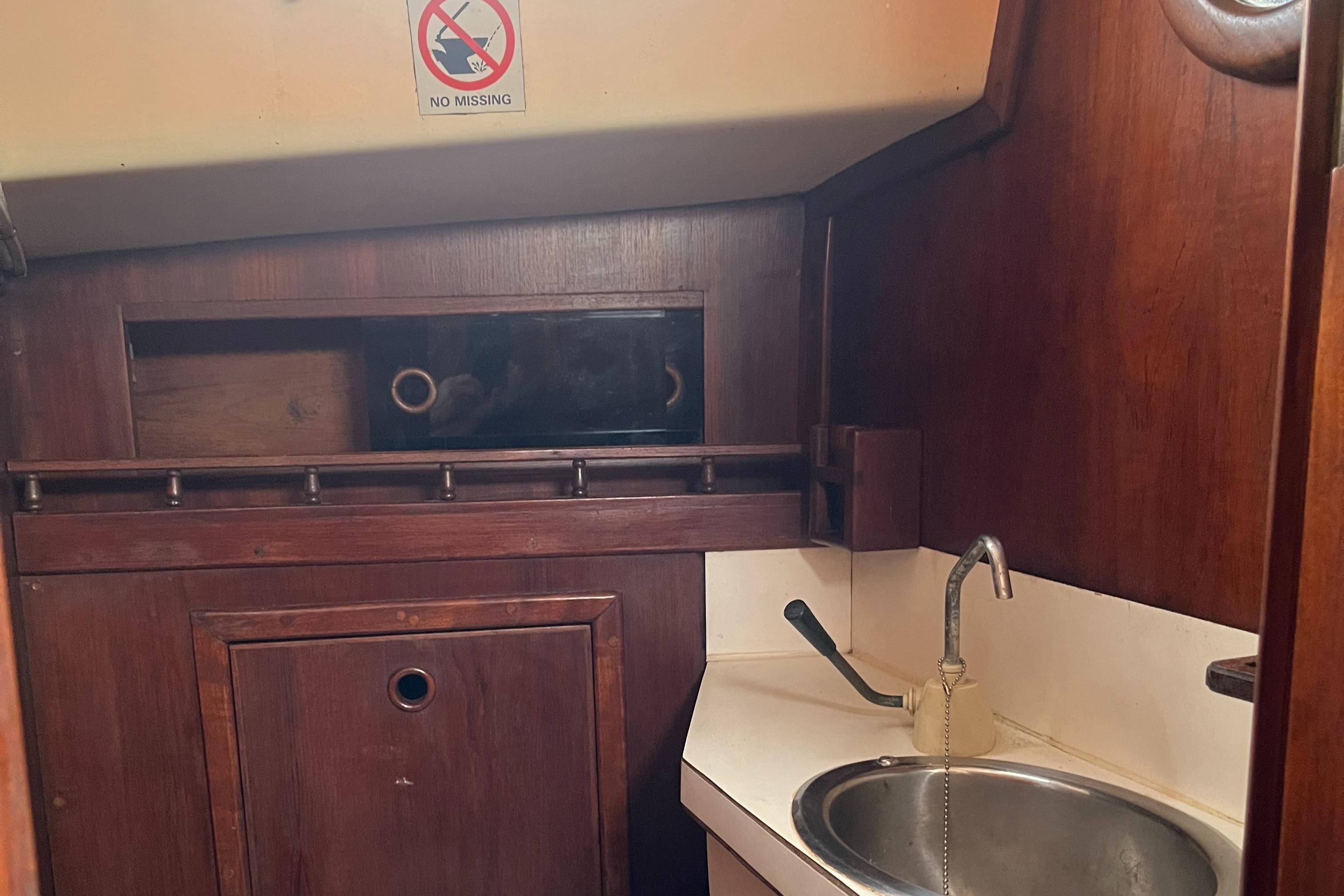 Interior of 1984 Grampian 30 sailboat with wooden cabinetry and small sink.