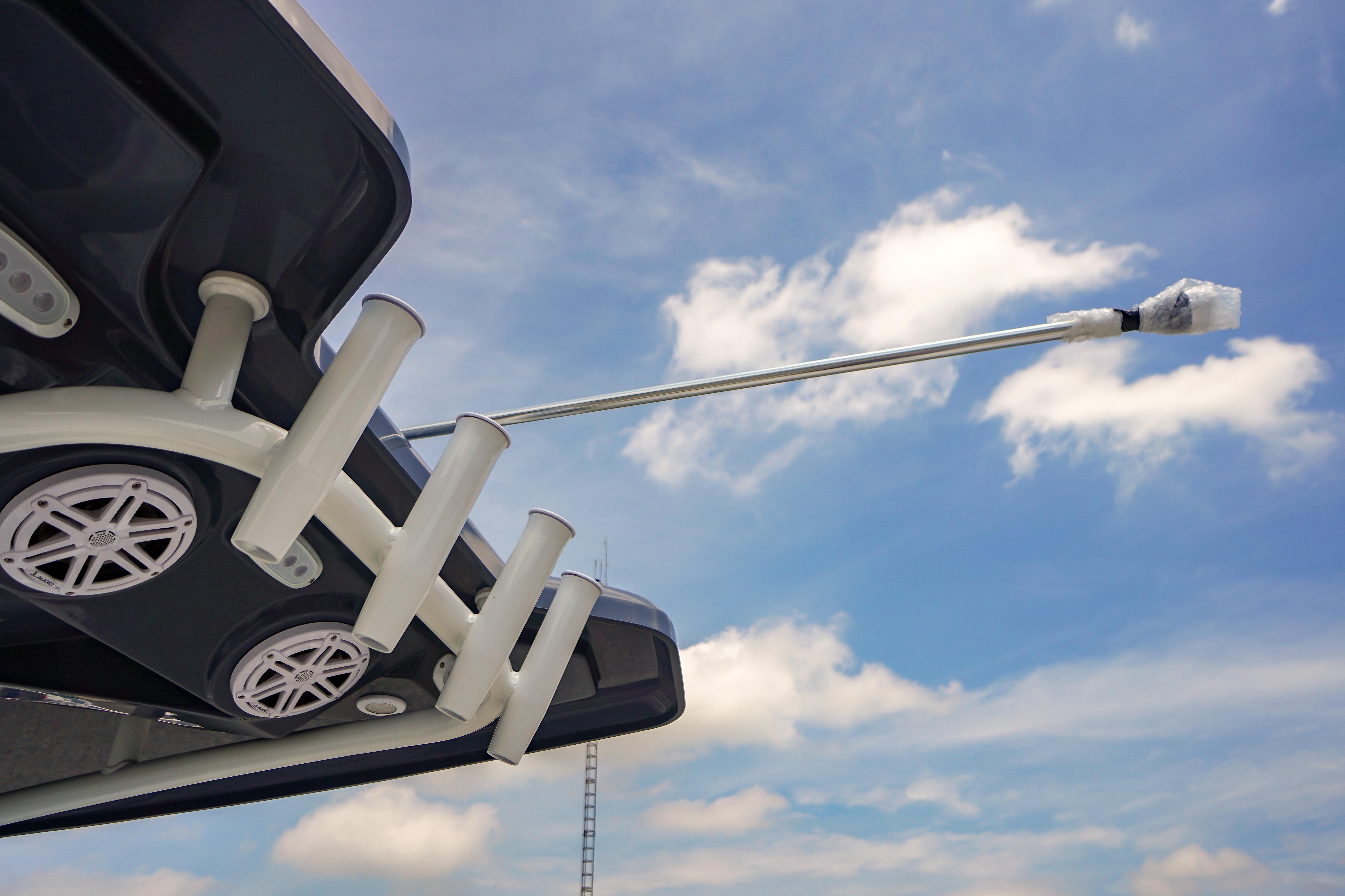 Tidewater 220 CC Adventure 2027 boat with rod holders and speakers against a blue sky.