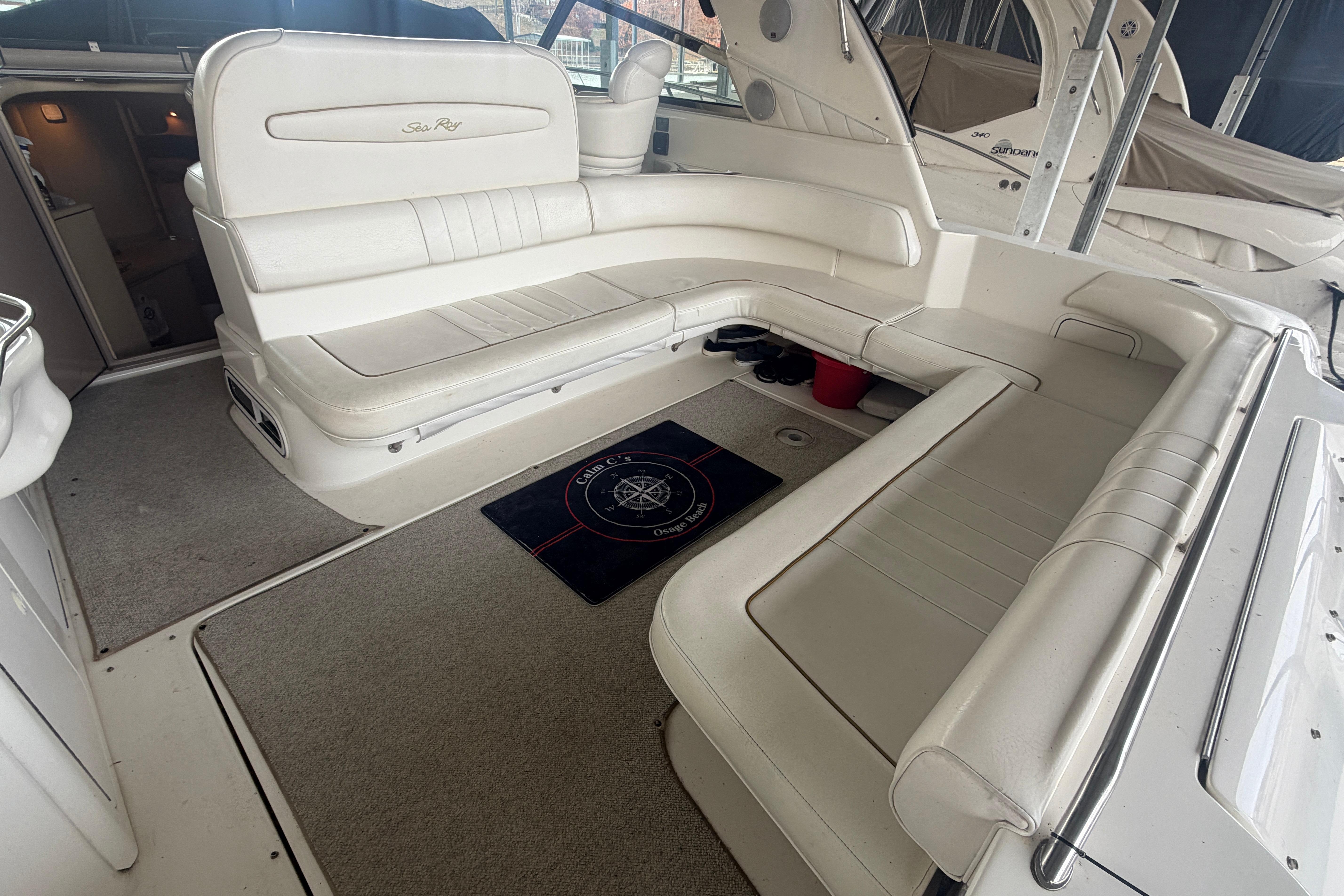 1999 Sea Ray 400 Sundancer interior with white seating and nautical-themed mat.
