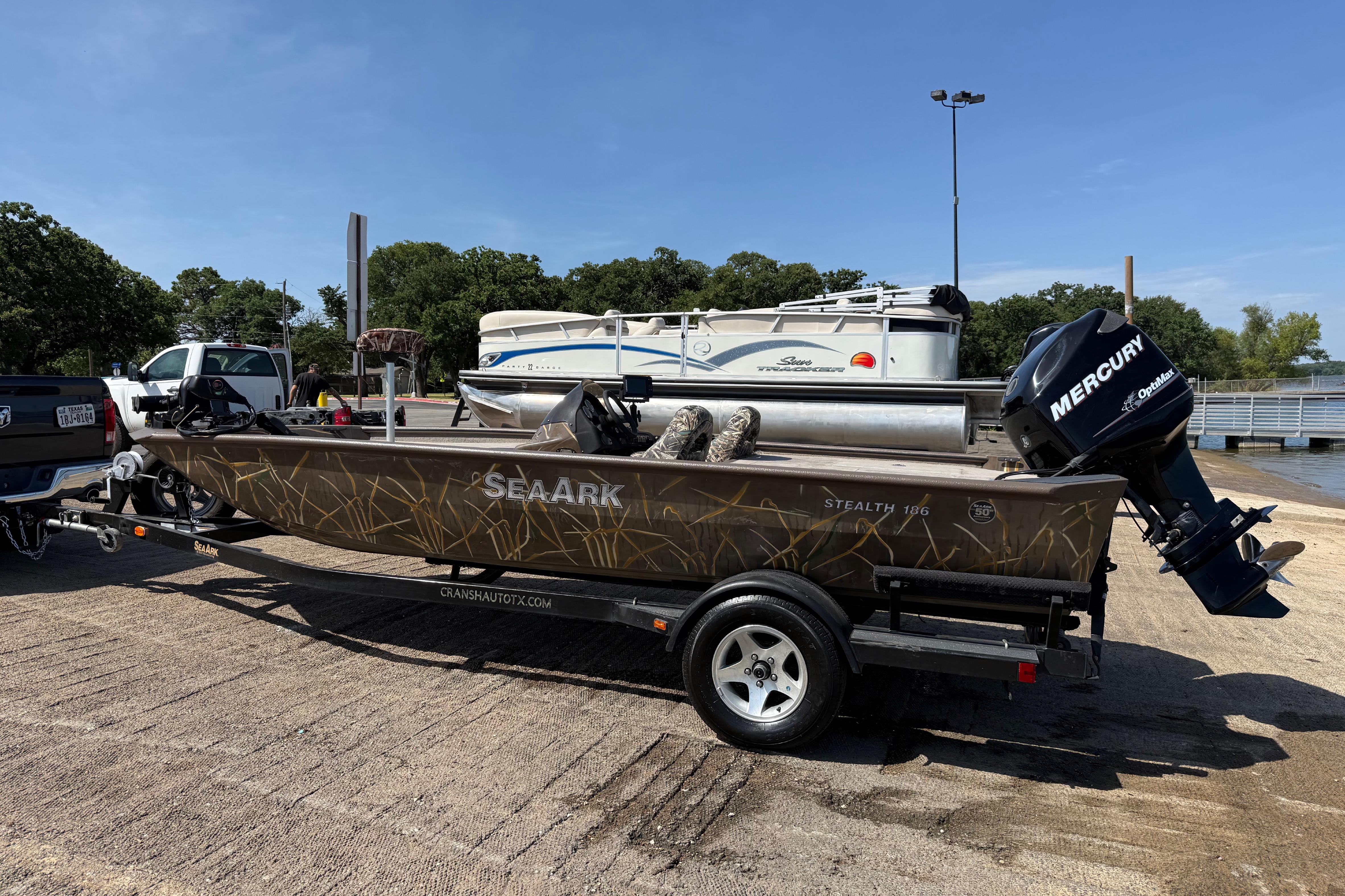 2010 SeaArk Stealth 190 boat on trailer with Mercury outboard motor at a boat ramp.