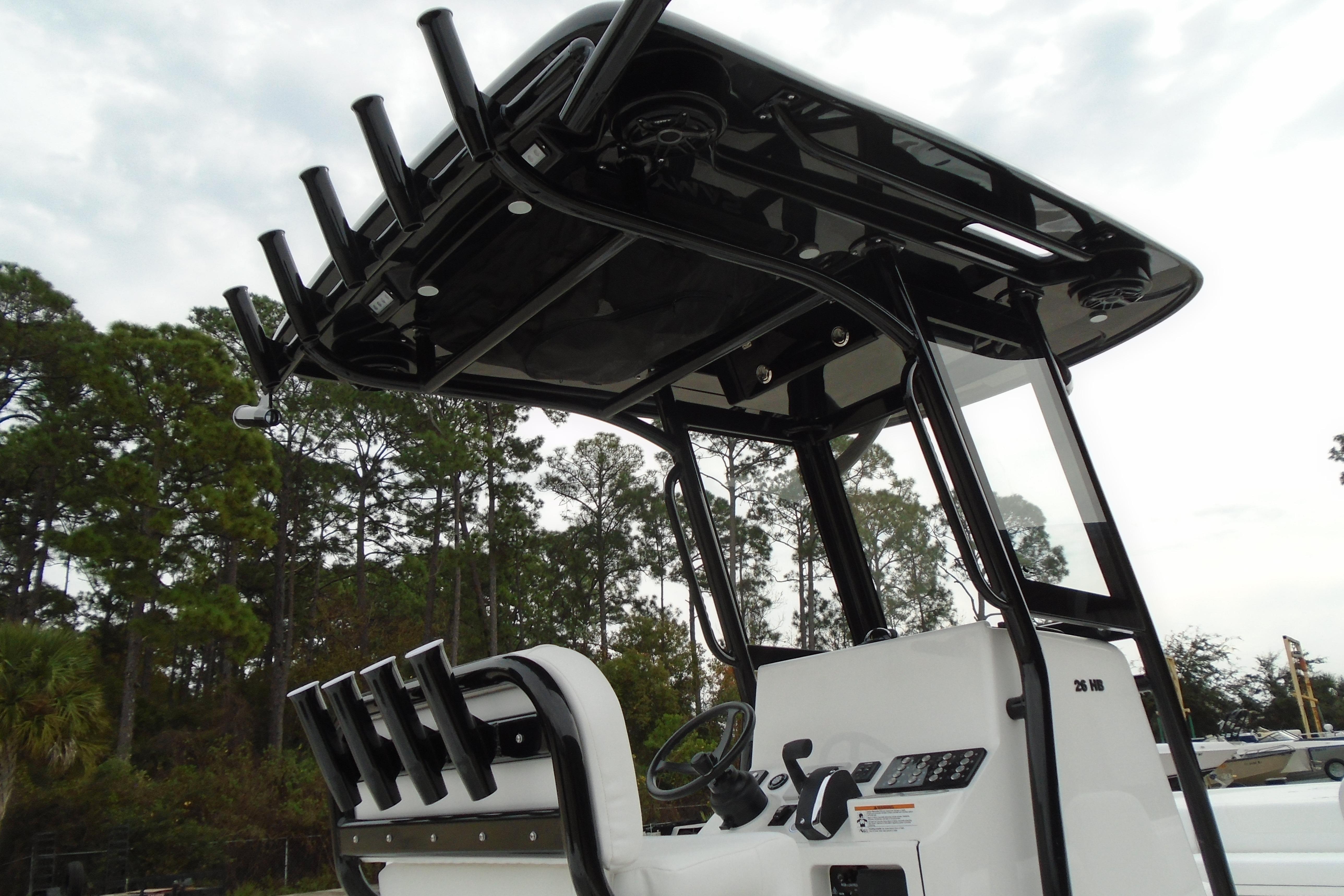 2026 Caymas 26 HB boat console with T-top and rod holders, set against a forested backdrop.