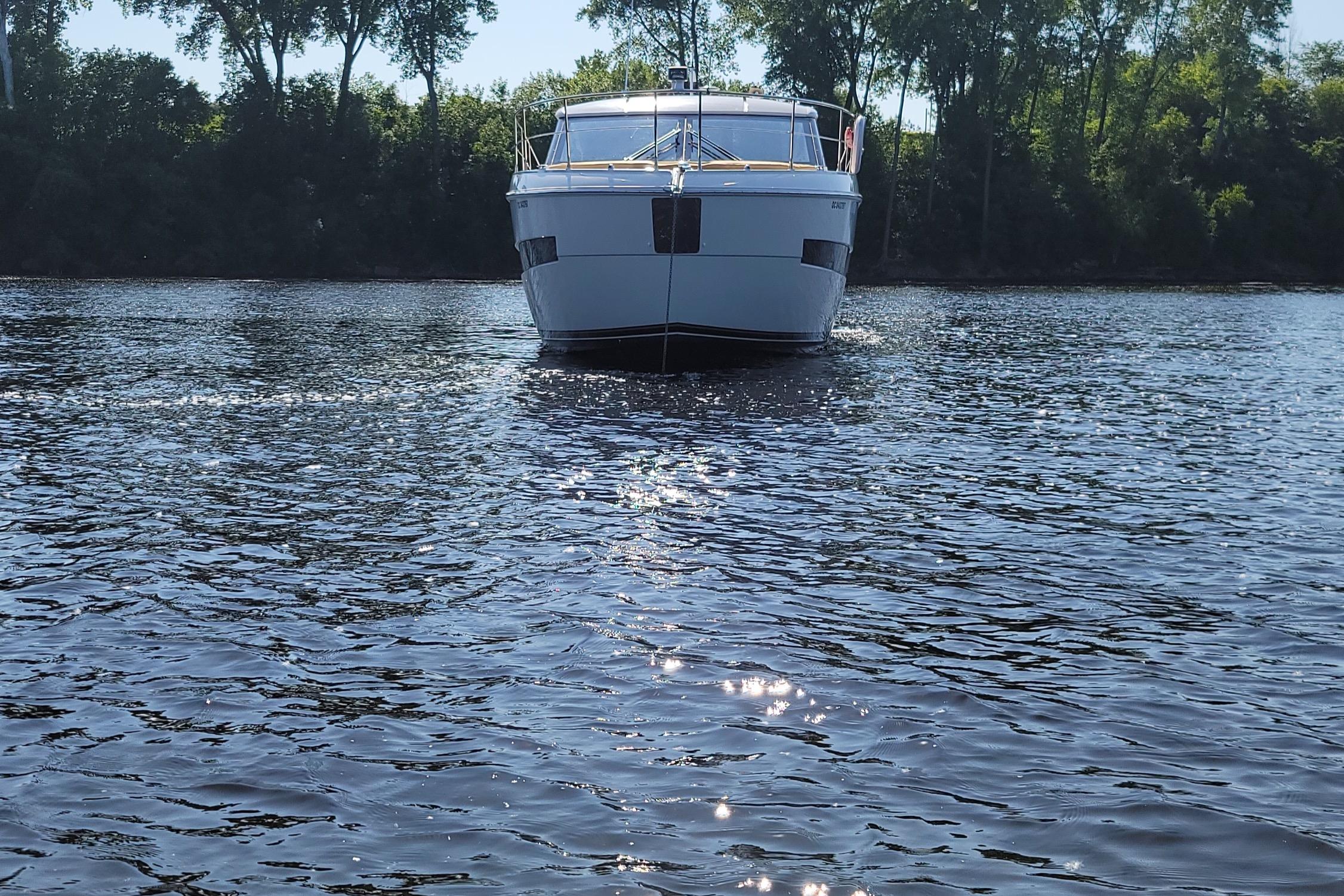 2016 Carver C37 yacht on a serene lake with trees in the background.