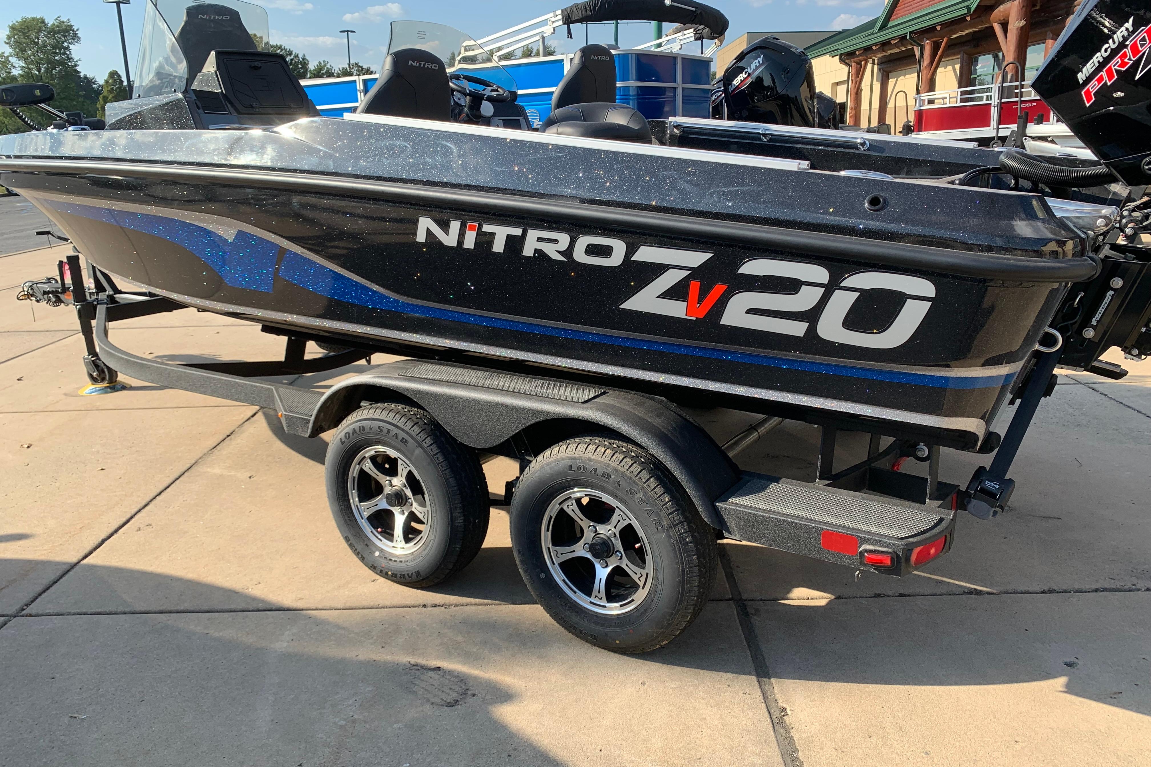 2025 Nitro ZV20 boat on trailer, black with blue accents, parked outdoors.