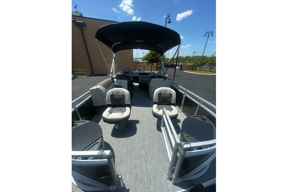 2026 Sun Tracker Fishin' Barge 20 DLX pontoon boat with seating and canopy under blue sky.