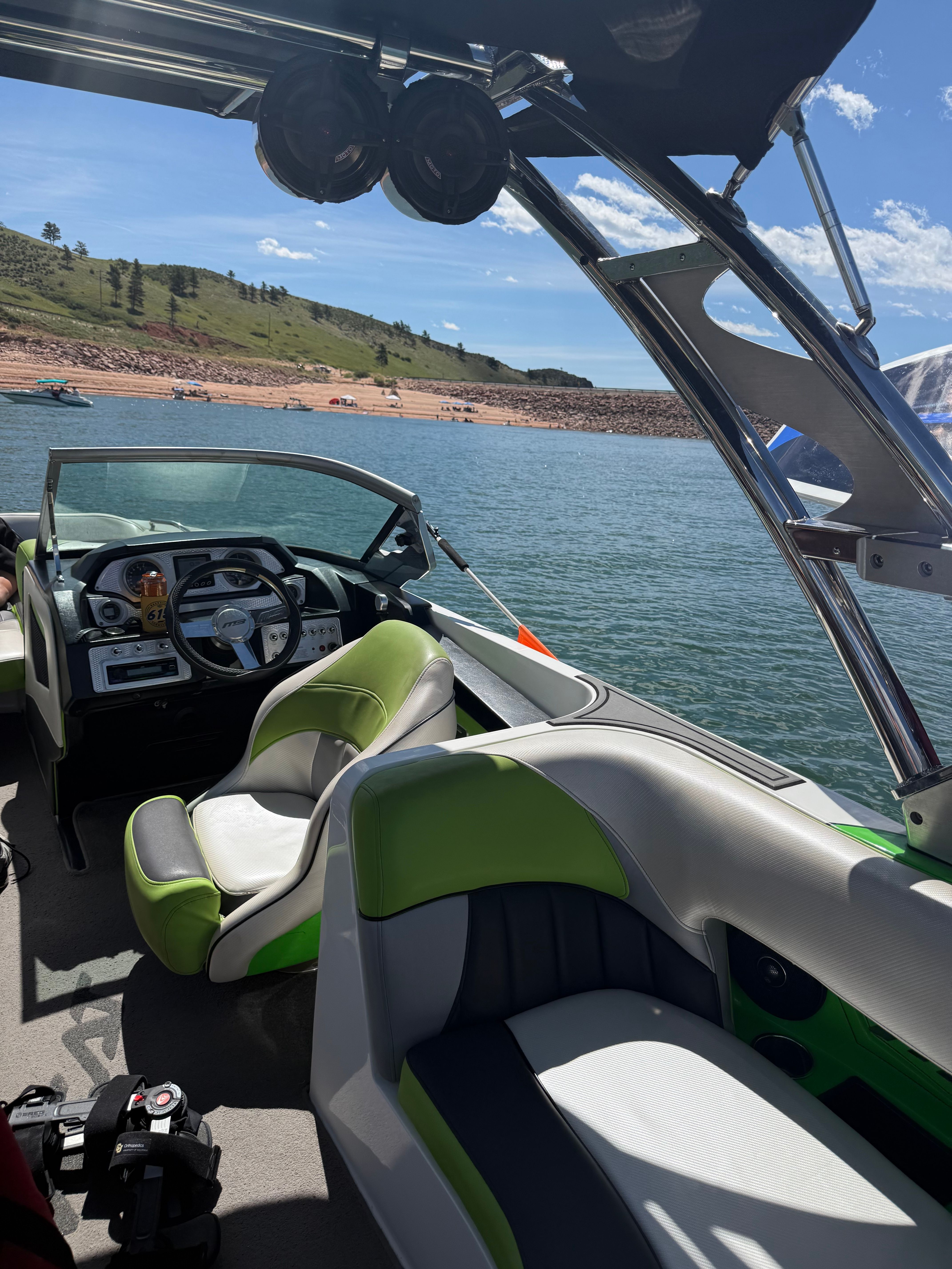 Interior view of a motorboat with green and white seats on a lake.