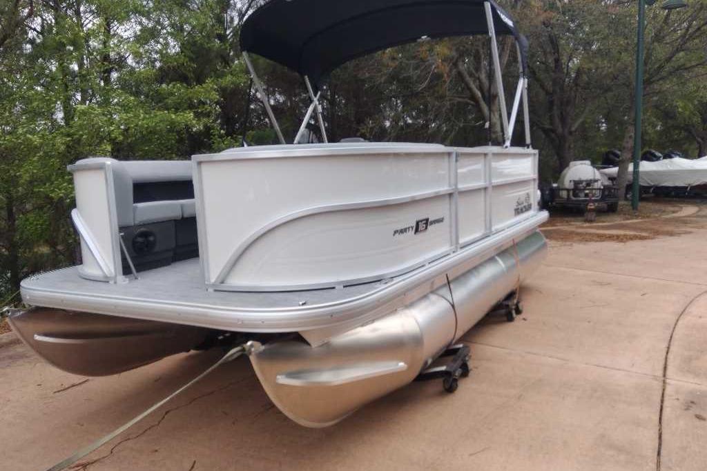 2026 Sun Tracker Party Barge 16 DLX pontoon boat on trailer, parked outdoors.