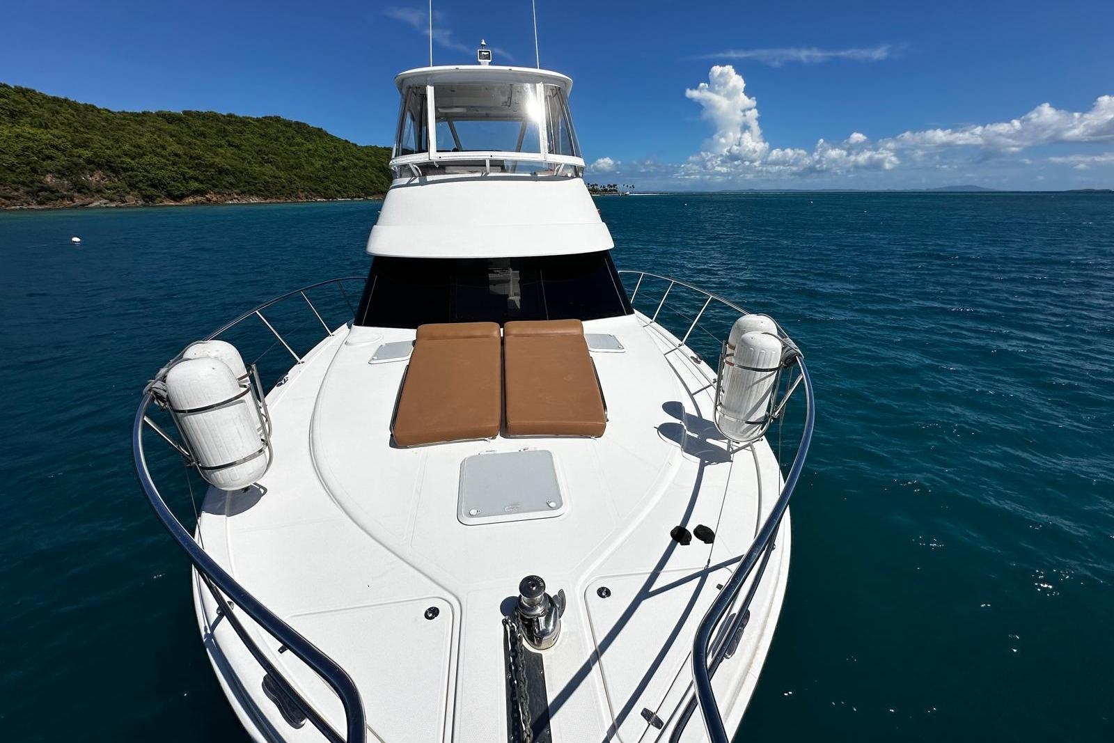 2012 Riviera 43 Flybridge yacht on calm blue waters, featuring spacious deck and scenic backdrop.