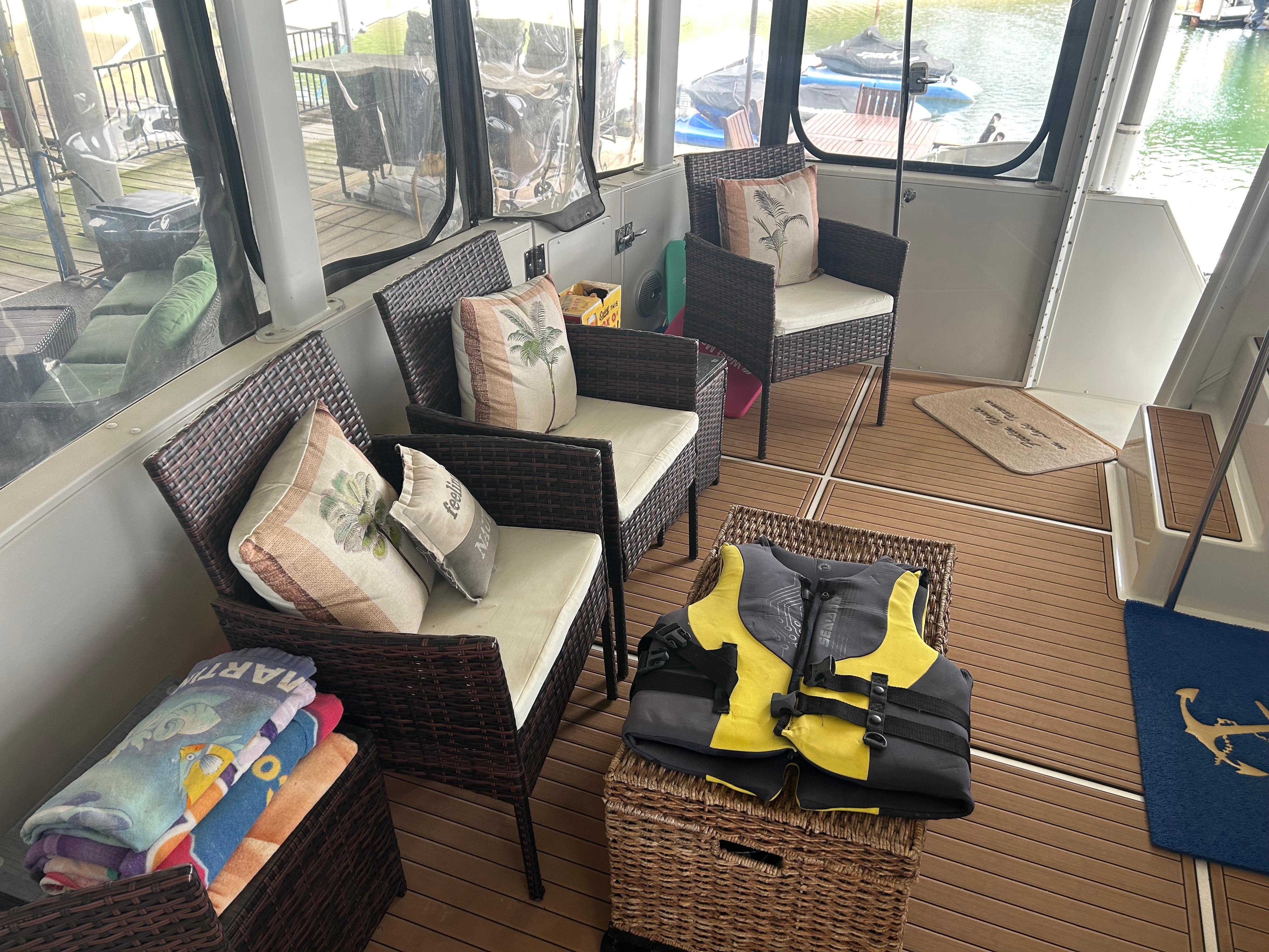 1996 Carver 440 Aft Cabin Motor Yacht interior with wicker chairs, life jackets, and colorful towels.