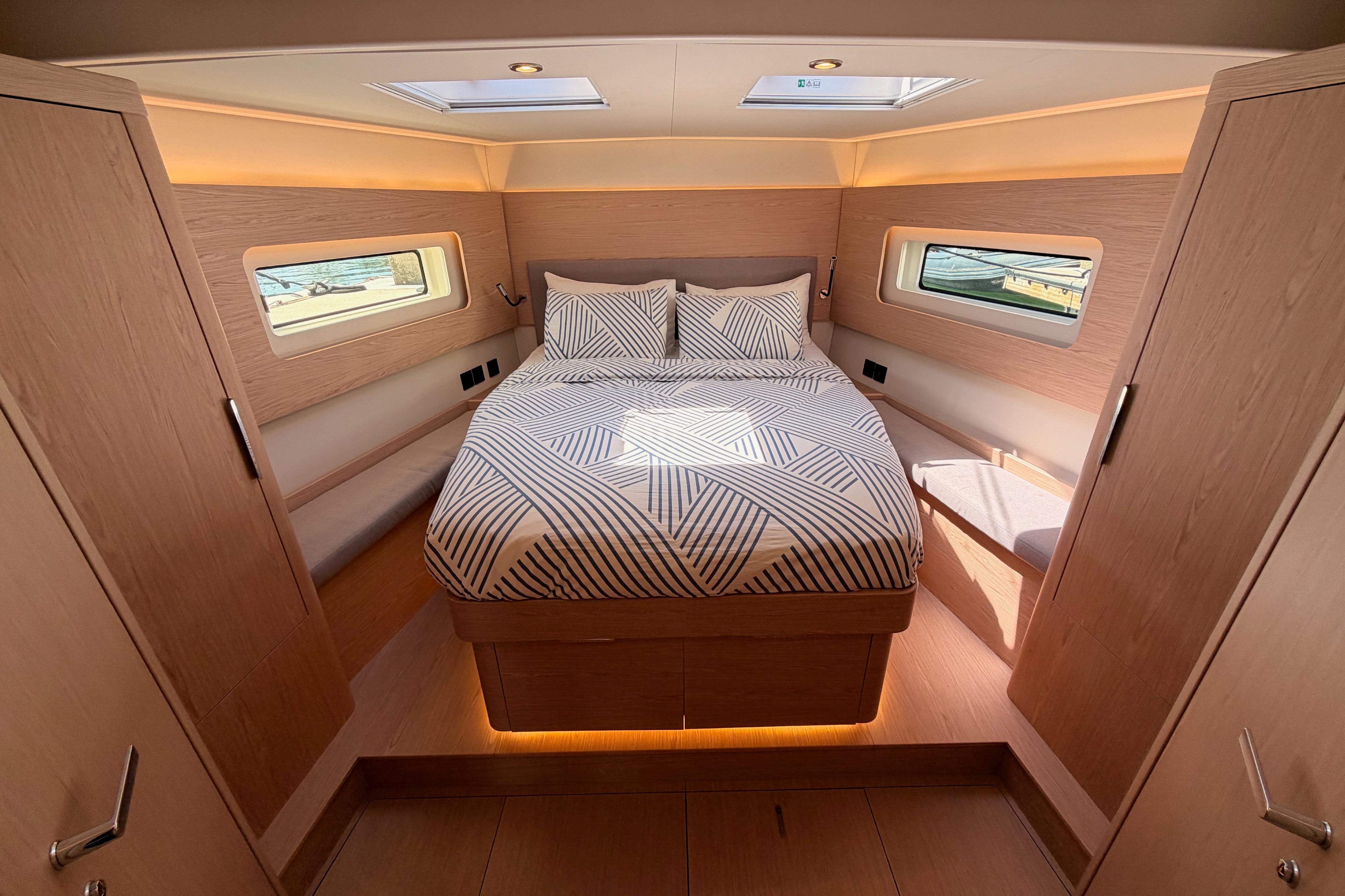 Luxurious cabin interior of 2022 Beneteau Oceanis Yacht 54 with modern bedding and natural light.