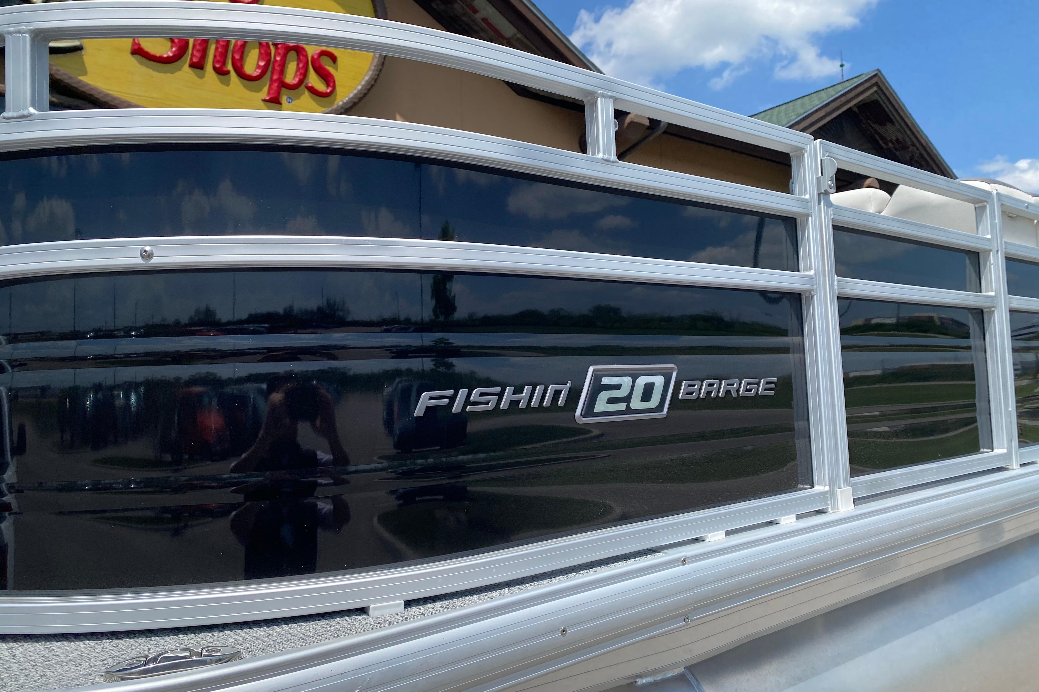 2026 Sun Tracker Fishin' Barge 20 DLX pontoon boat at outdoor store.