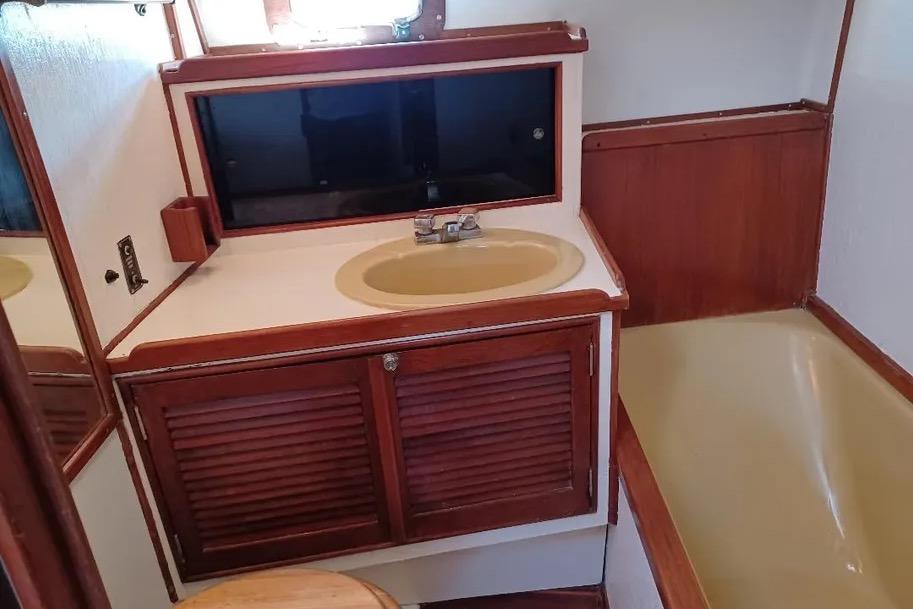 1977 Morgan Out Island 51 yacht bathroom with wooden cabinetry and beige fixtures.