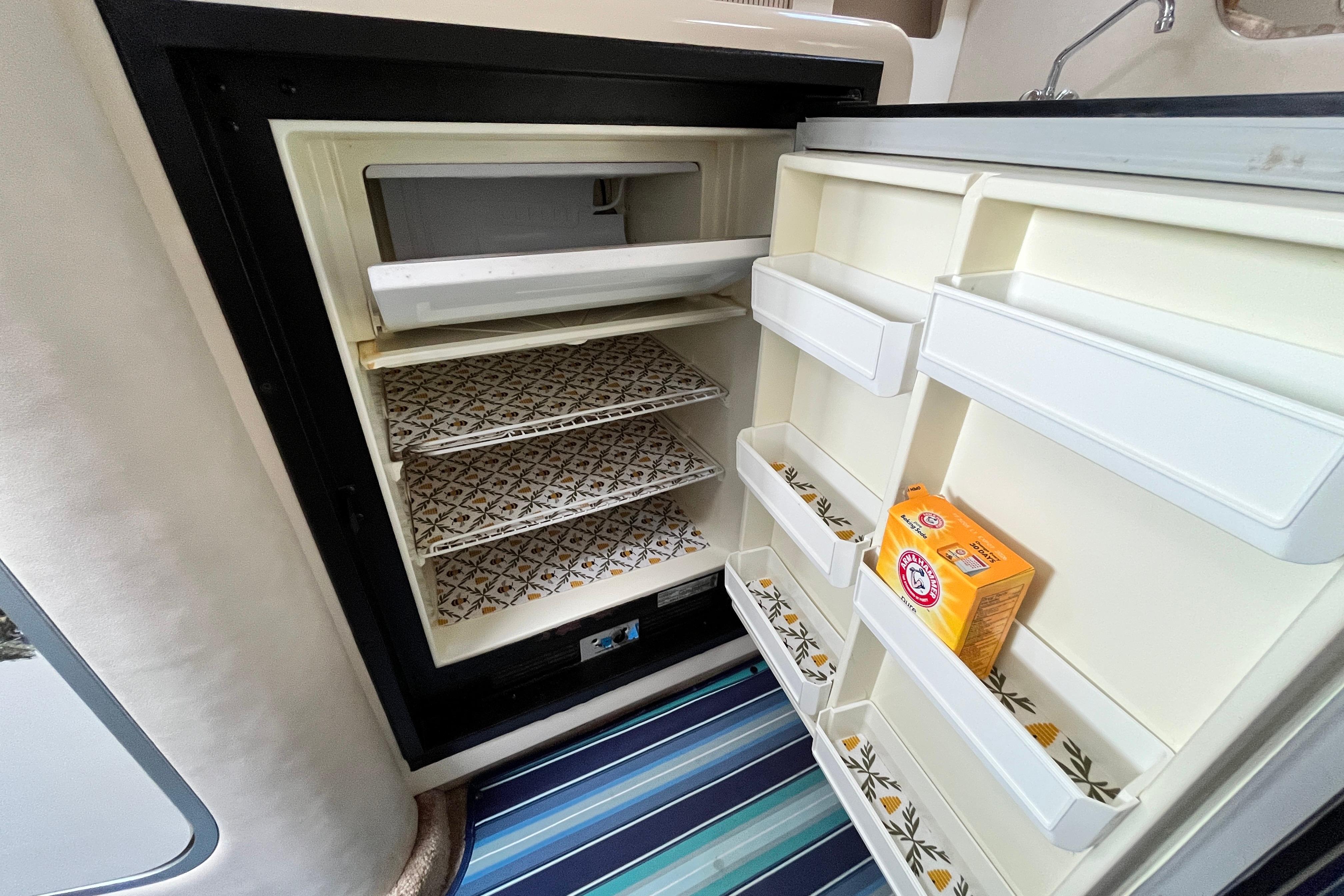 Open refrigerator in 1995 Sea Ray Sundancer 330 yacht, featuring organized shelves and baking soda box.