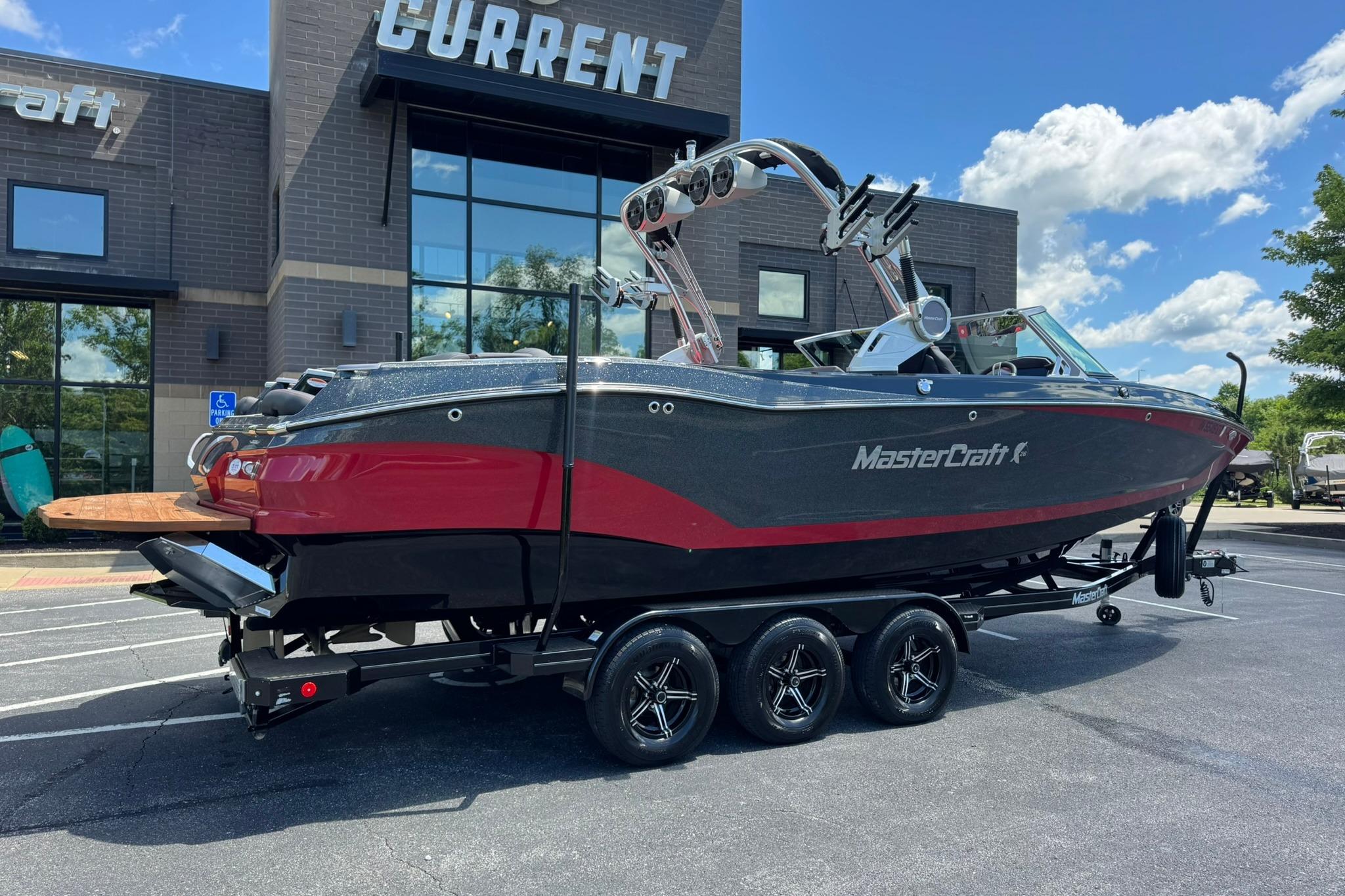 2021 MasterCraft X26 boat on trailer, parked outside a building under a blue sky.