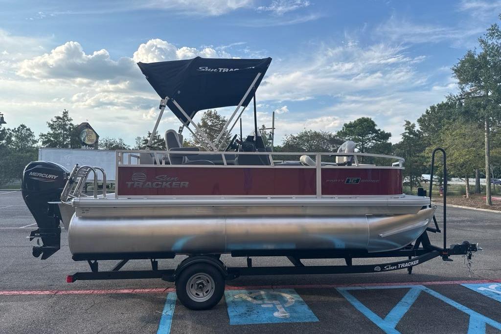 2026 Sun Tracker Bass Buggy 16 XL Select pontoon boat on trailer in parking lot.