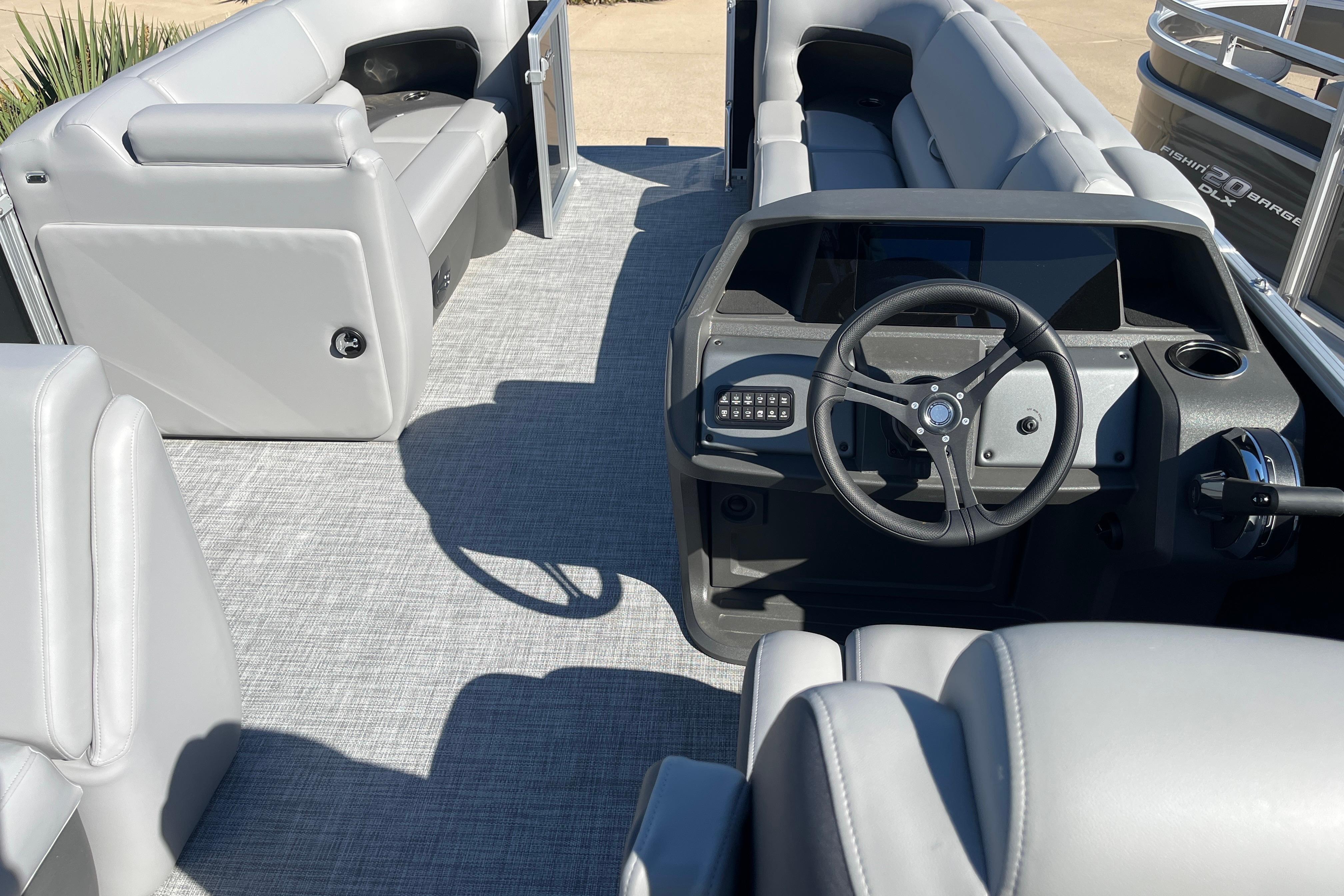 2026 Sun Tracker Party Barge 20 DLX interior with gray seating and steering console.