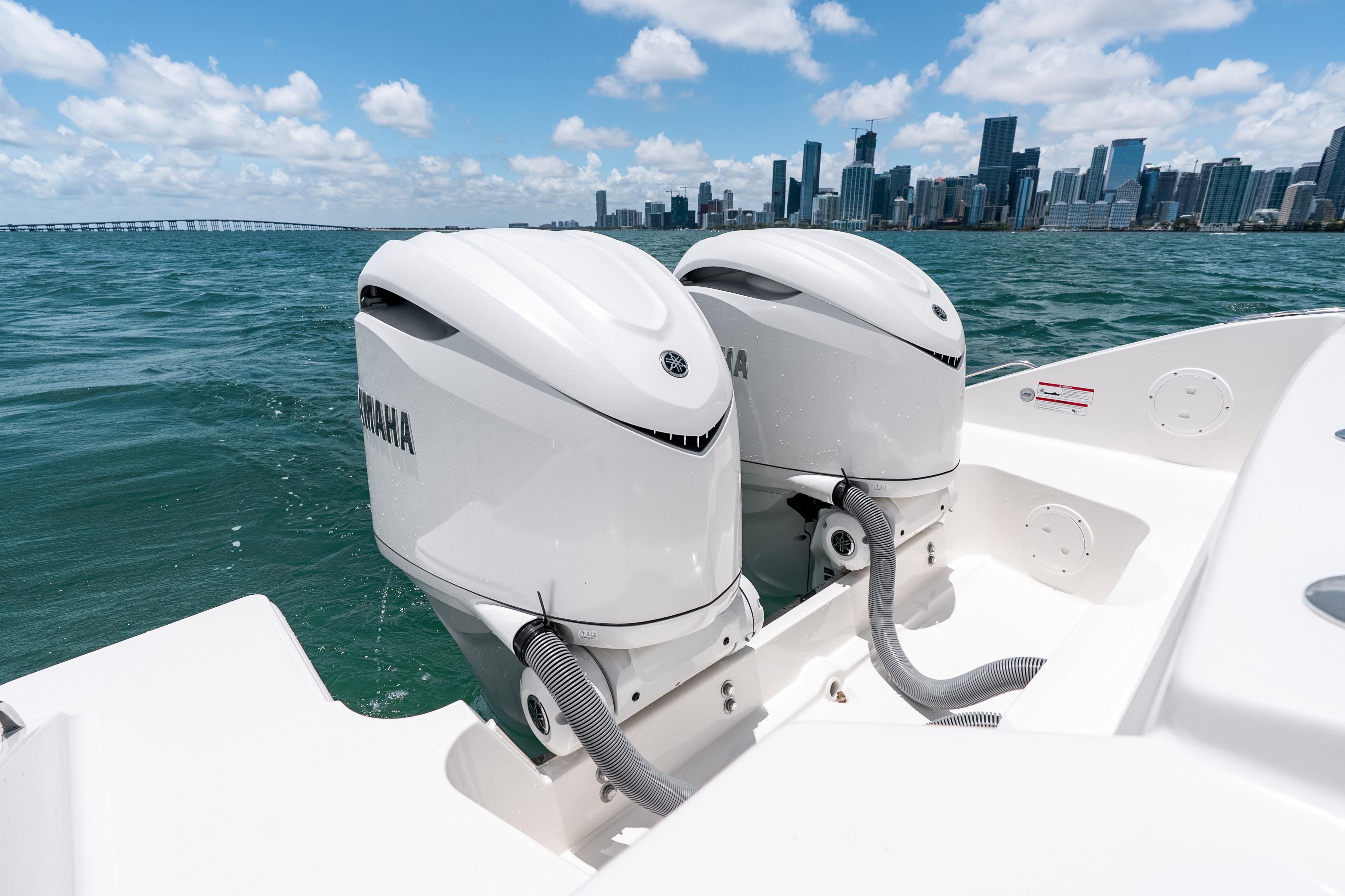 2026 Pursuit DC 326 Dual Console with twin Yamaha outboards, city skyline in background.