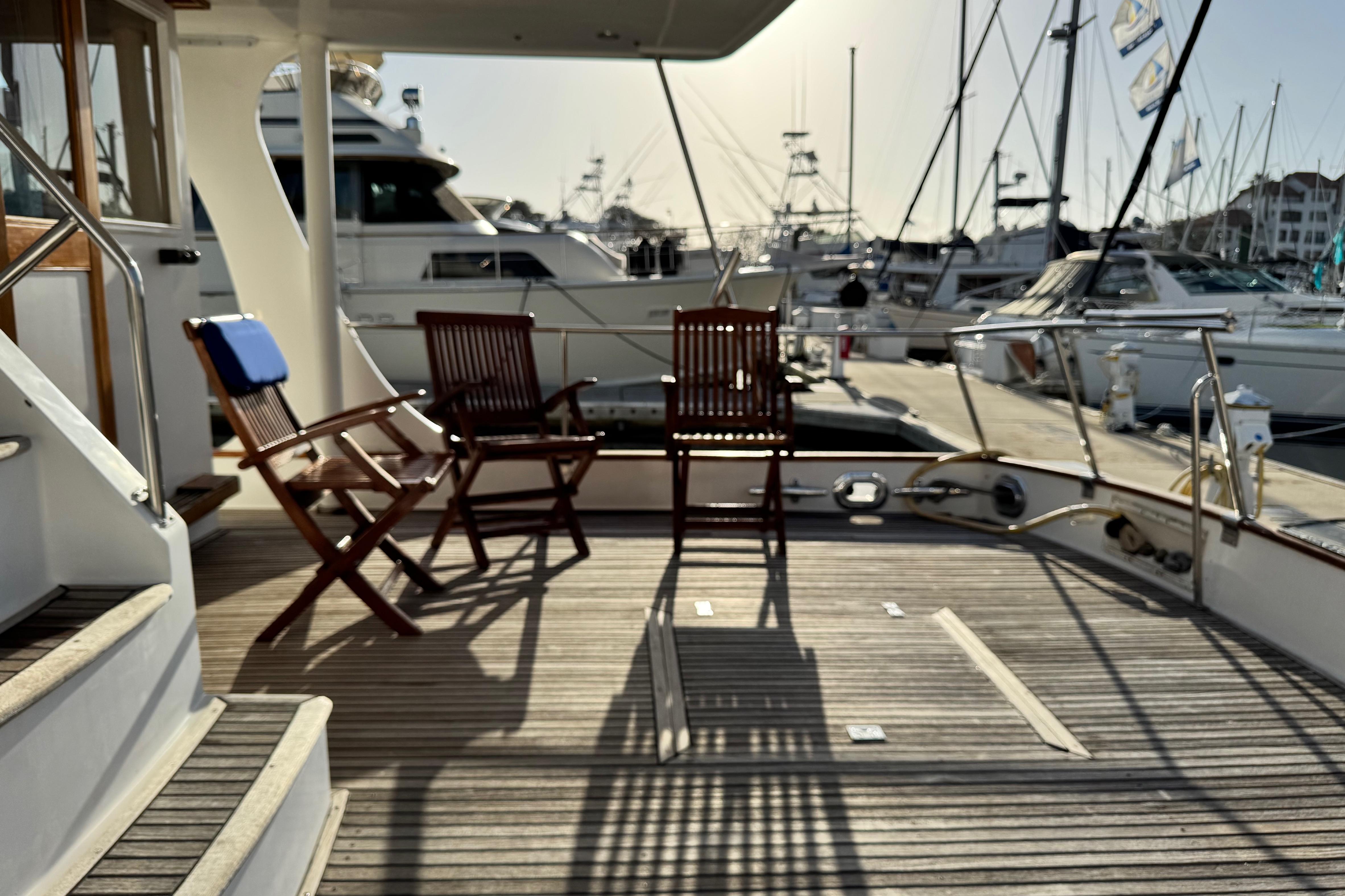 Deck of 2000 Grand Banks 52 Europa yacht with wooden chairs at marina.