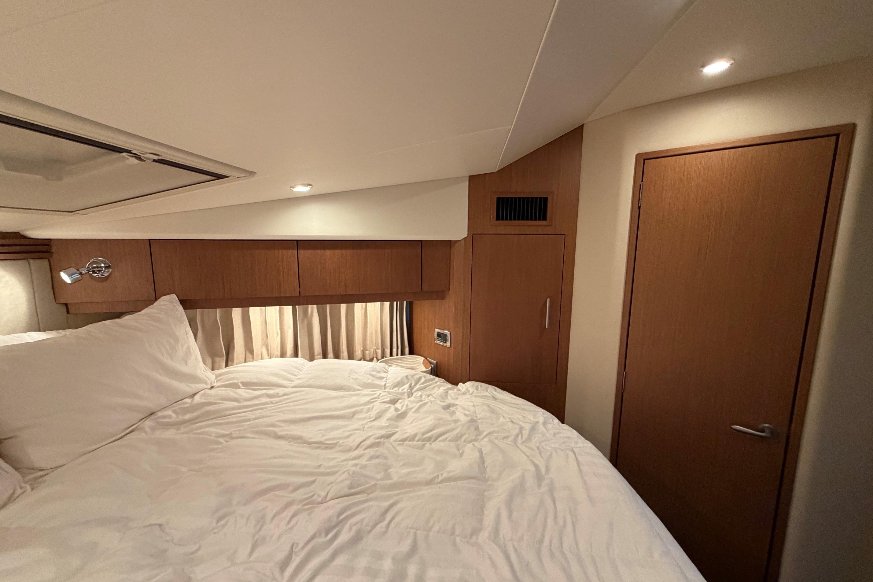 Cozy bedroom interior of 2011 Carver 44 Sojourn yacht with wood paneling and soft lighting.