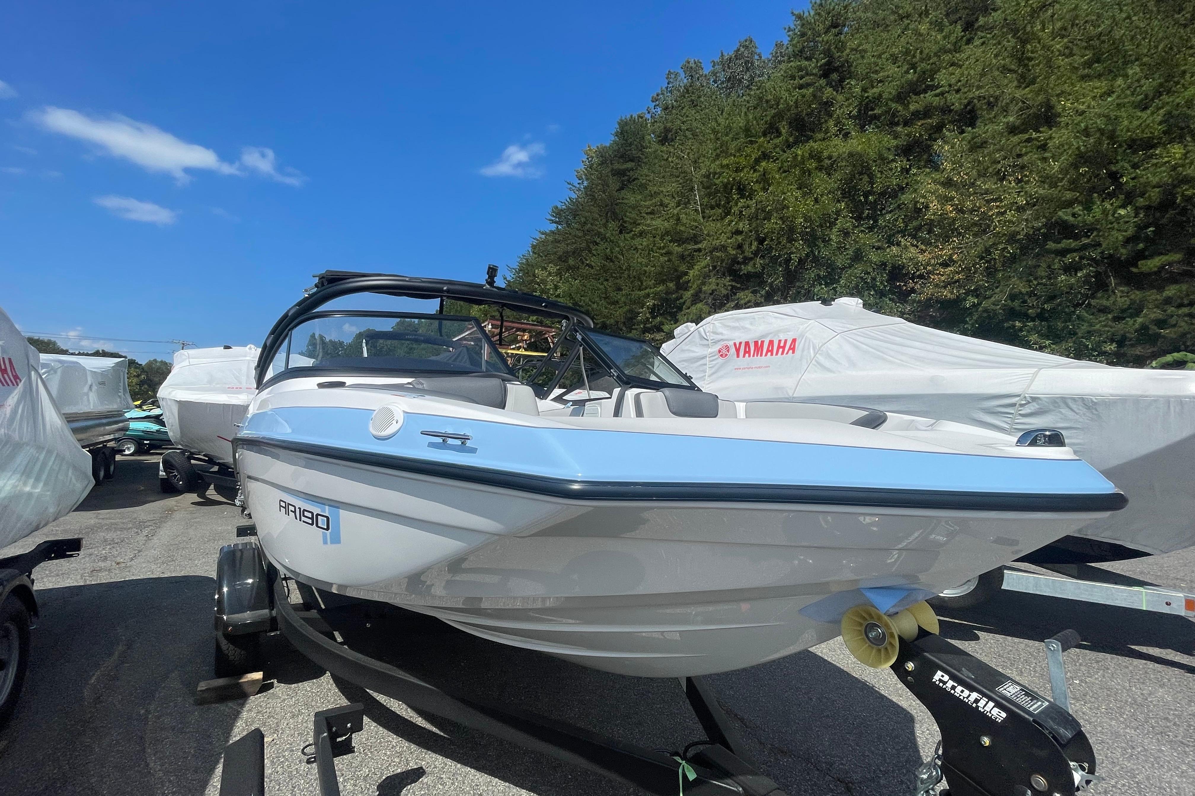 2026 Yamaha AR190 boat on trailer, surrounded by trees and blue sky.