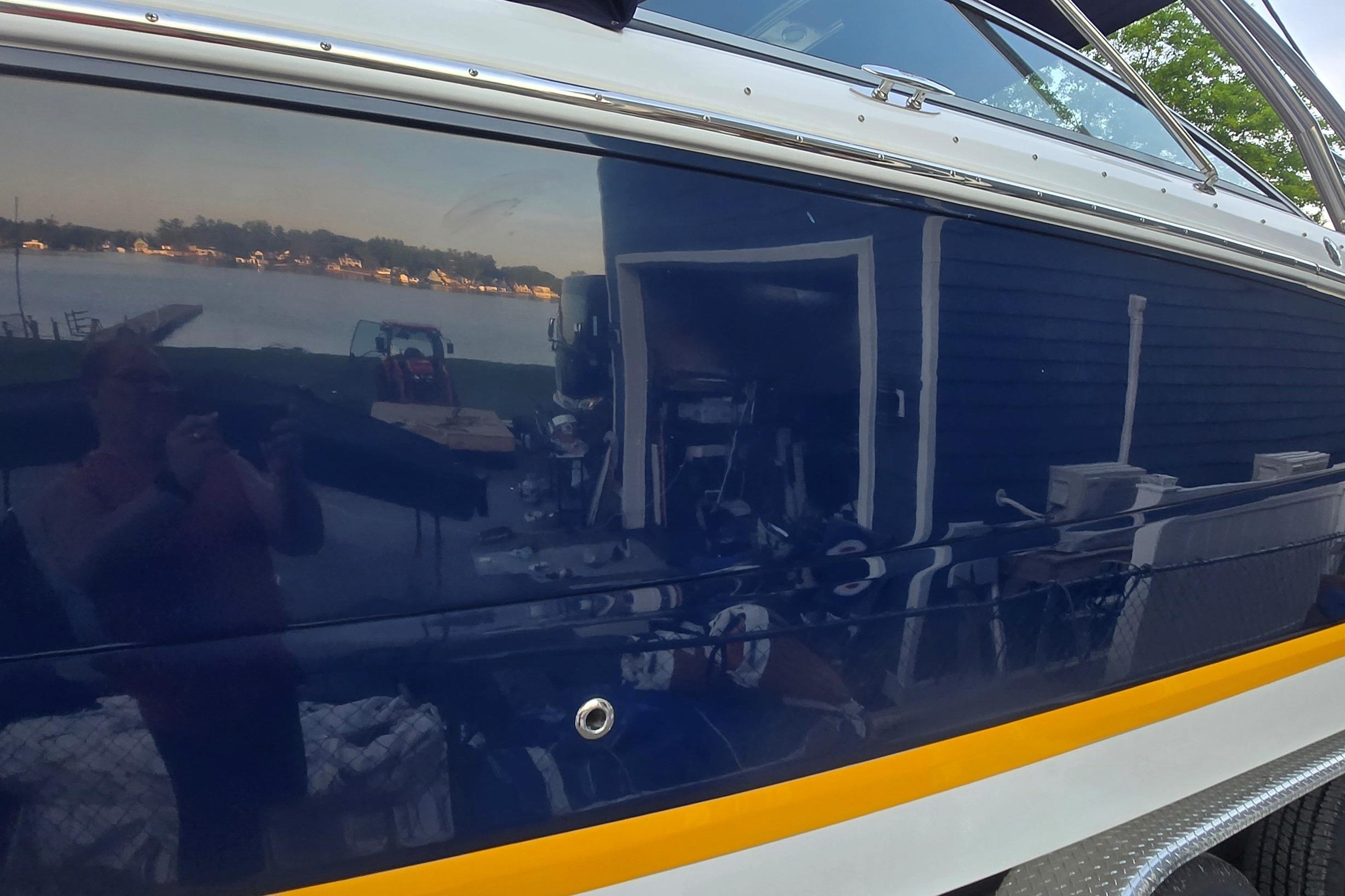 2013 Cobalt 296 boat with reflective blue hull near a lakeside view.