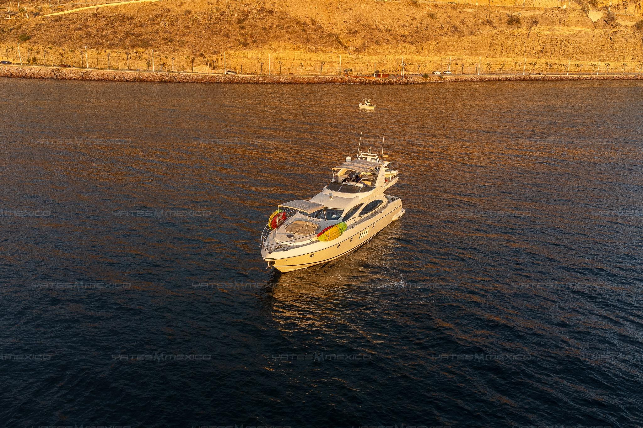 Luxury Azimut 68 Plus yacht cruising near a scenic coastline at sunset, 2004 model.