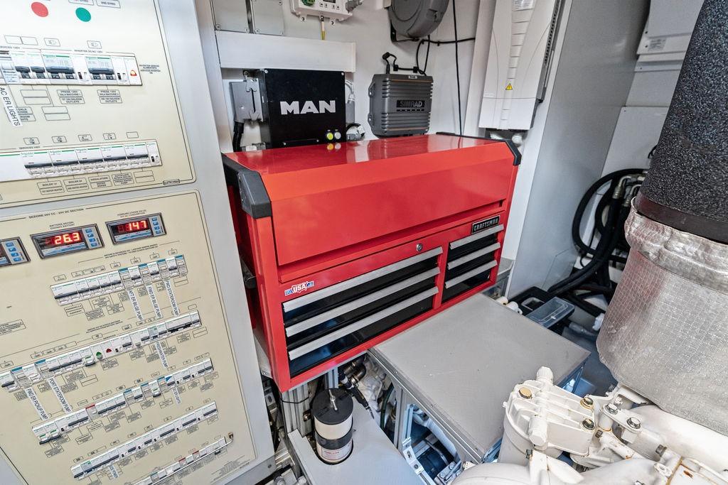 Engine room of 2018 Ferretti Yachts 850 Motoryacht with control panel and red toolbox.