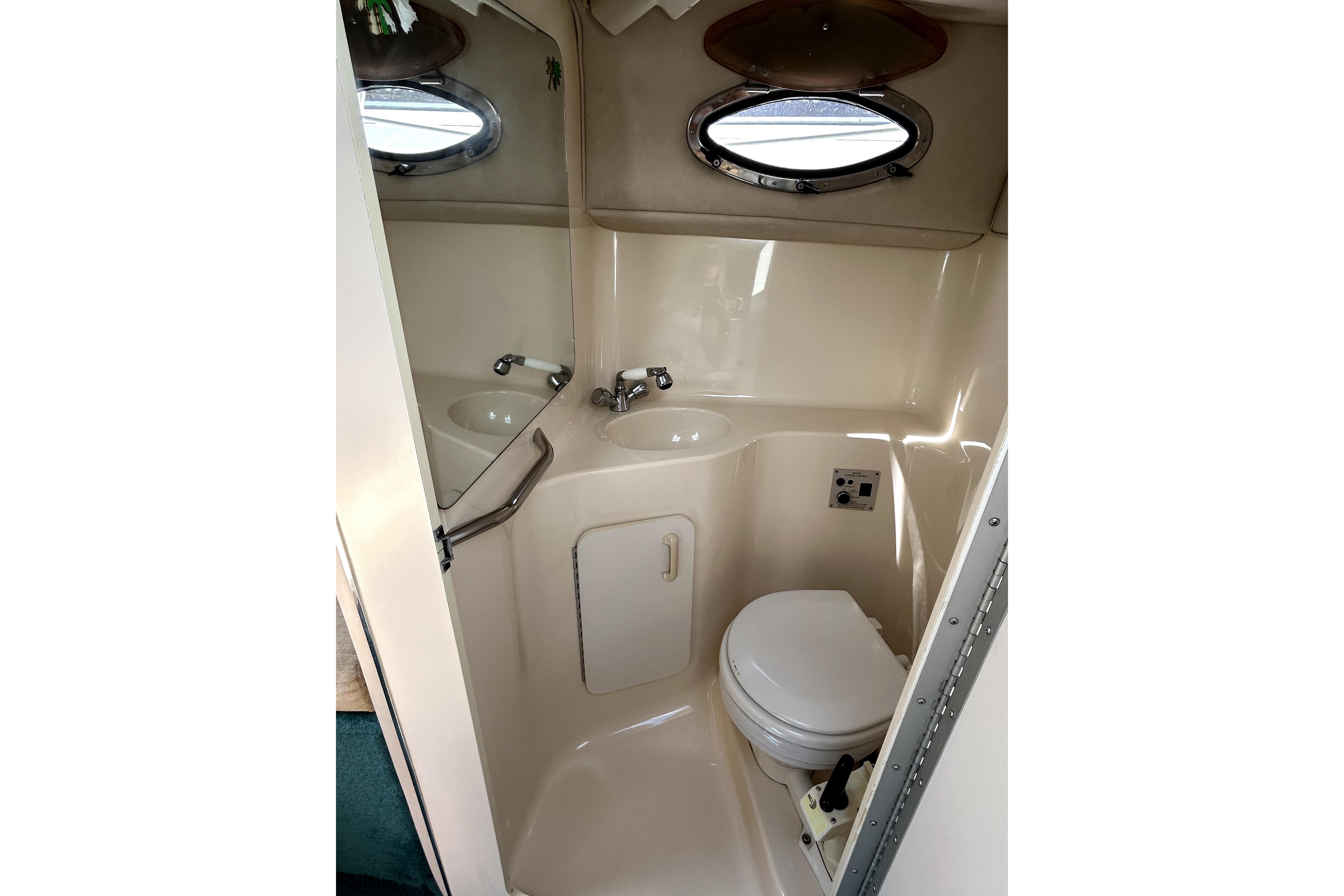 1995 Sea Ray 250 Sundancer boat bathroom with sink, toilet, and porthole window.