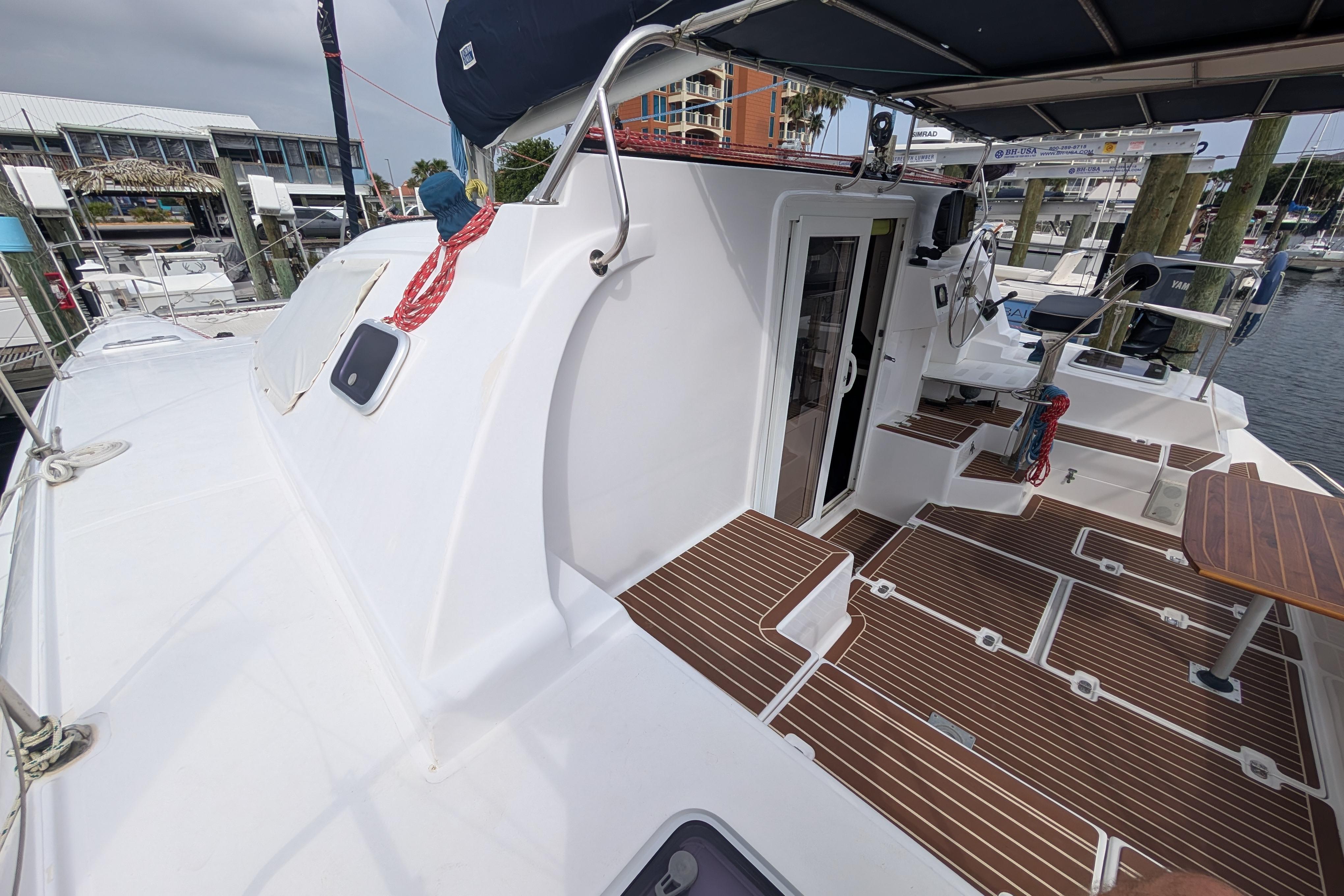 Island Spirit 37 catamaran deck, 1999 model, featuring teak flooring and marina backdrop.