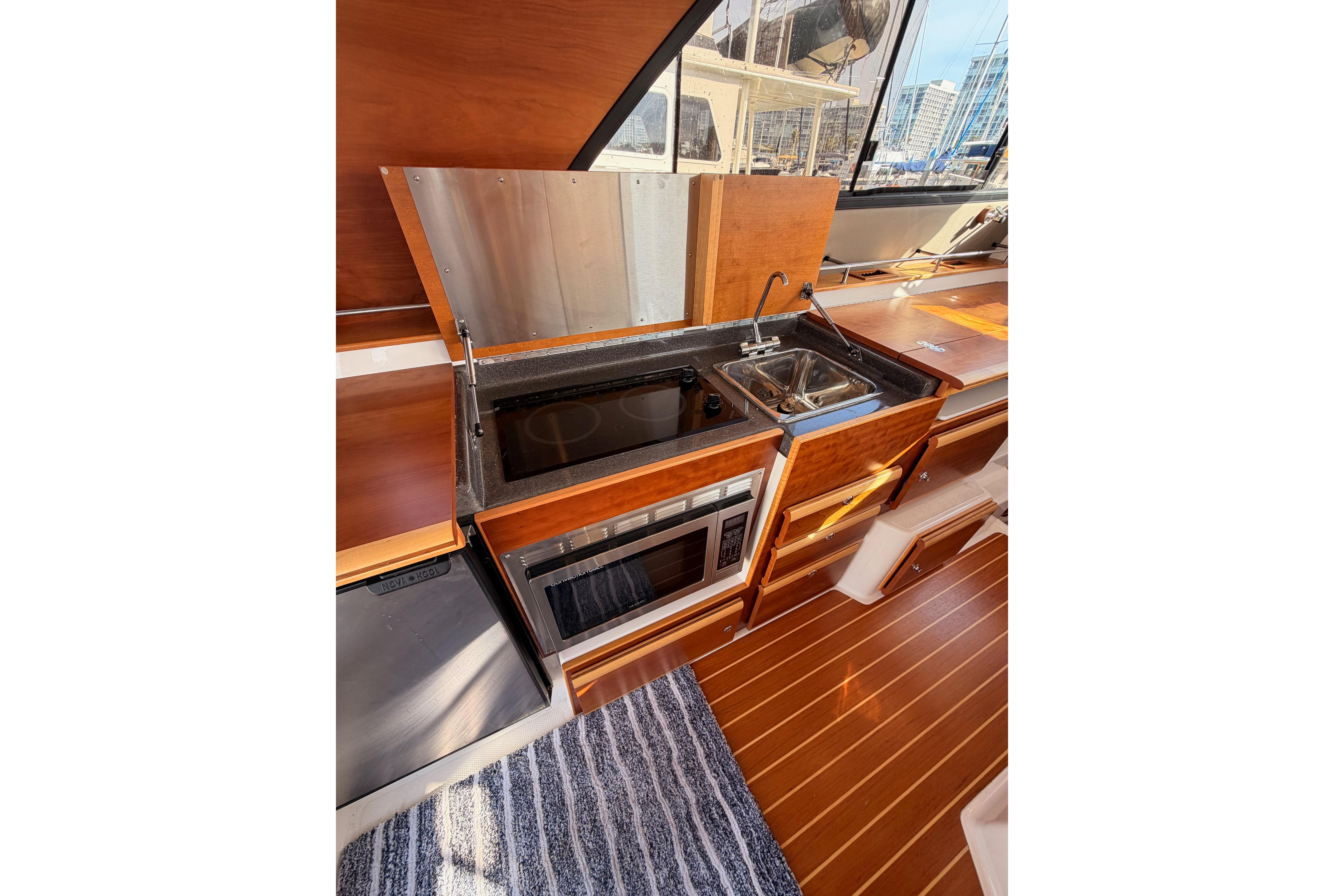 2021 Cutwater C-32 CB yacht interior kitchen with sink, stove, and microwave.