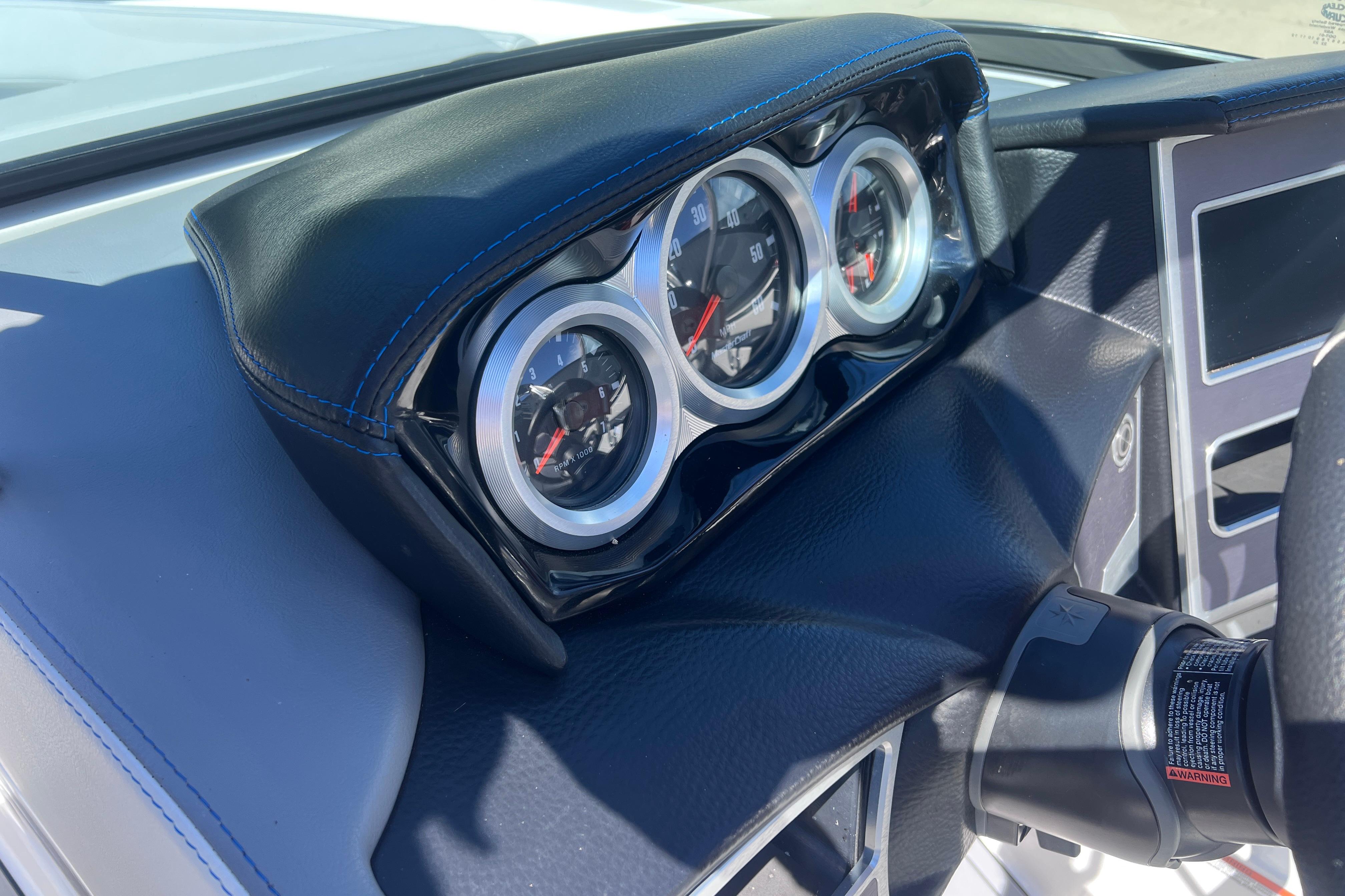 Dashboard of a 2021 MasterCraft XT23 boat with gauges and steering wheel.