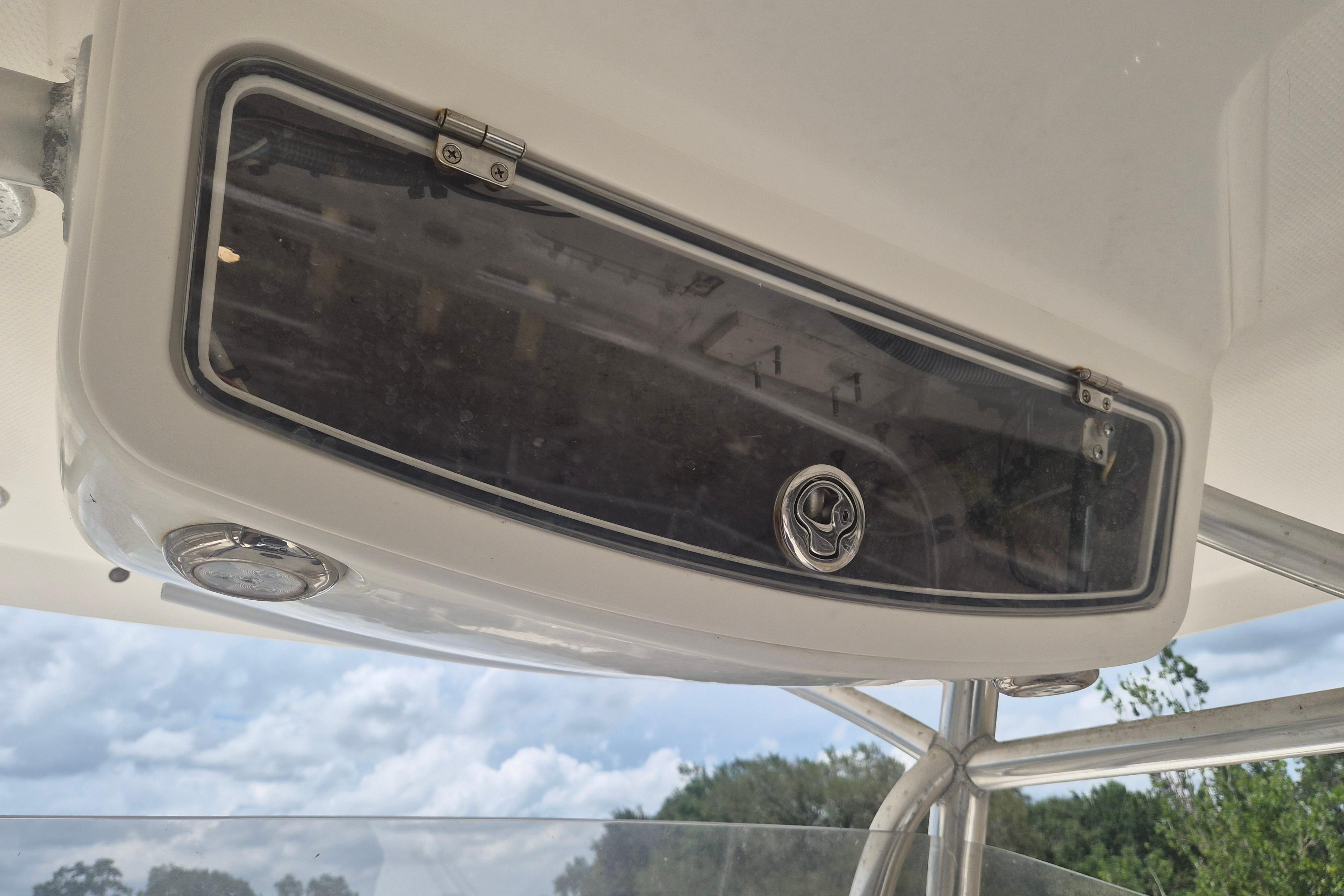 2006 Century 2900 Center Console boat storage compartment with latch, under a clear blue sky.
