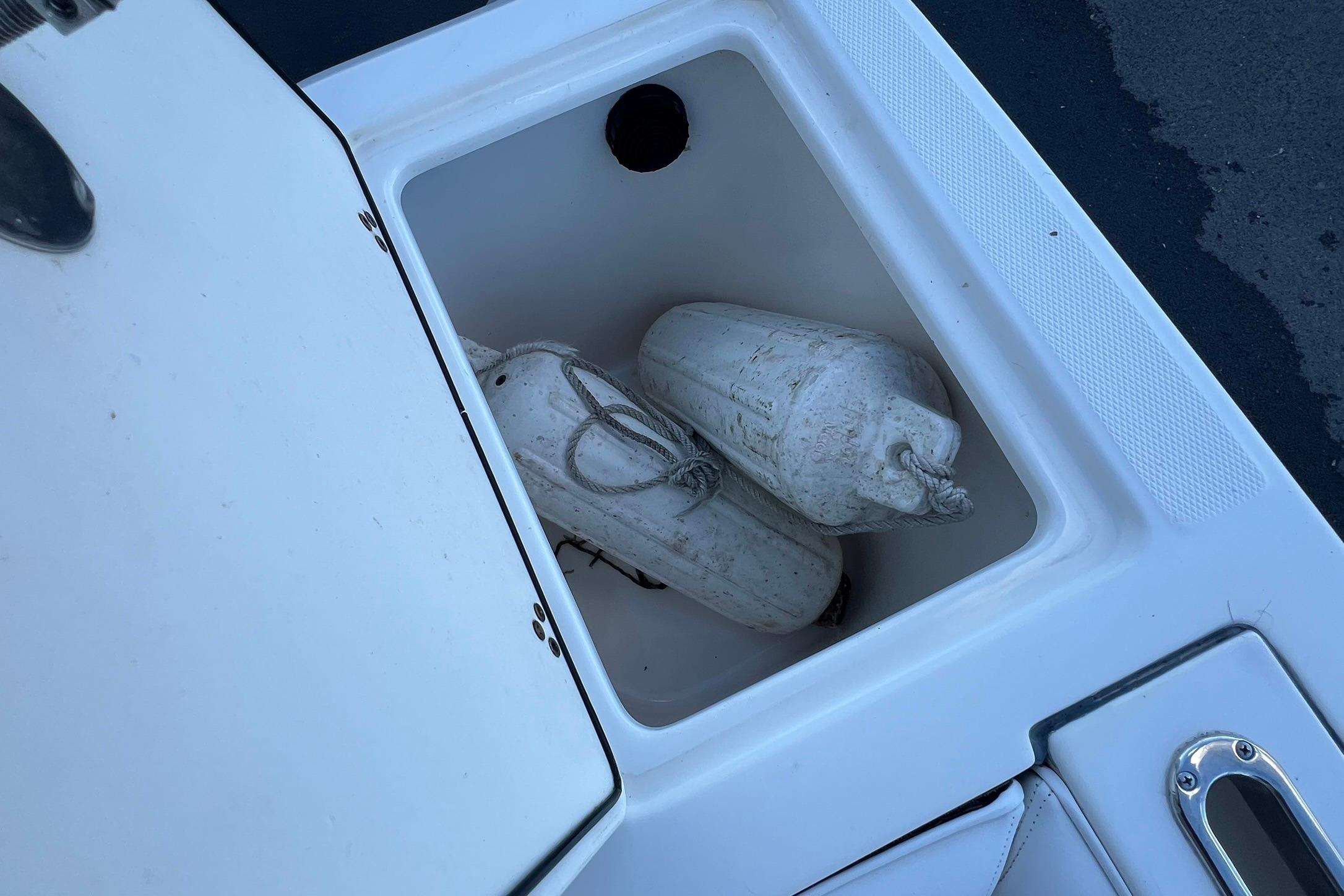Storage compartment on a 2006 Edgewater 245CC boat with white fenders inside.