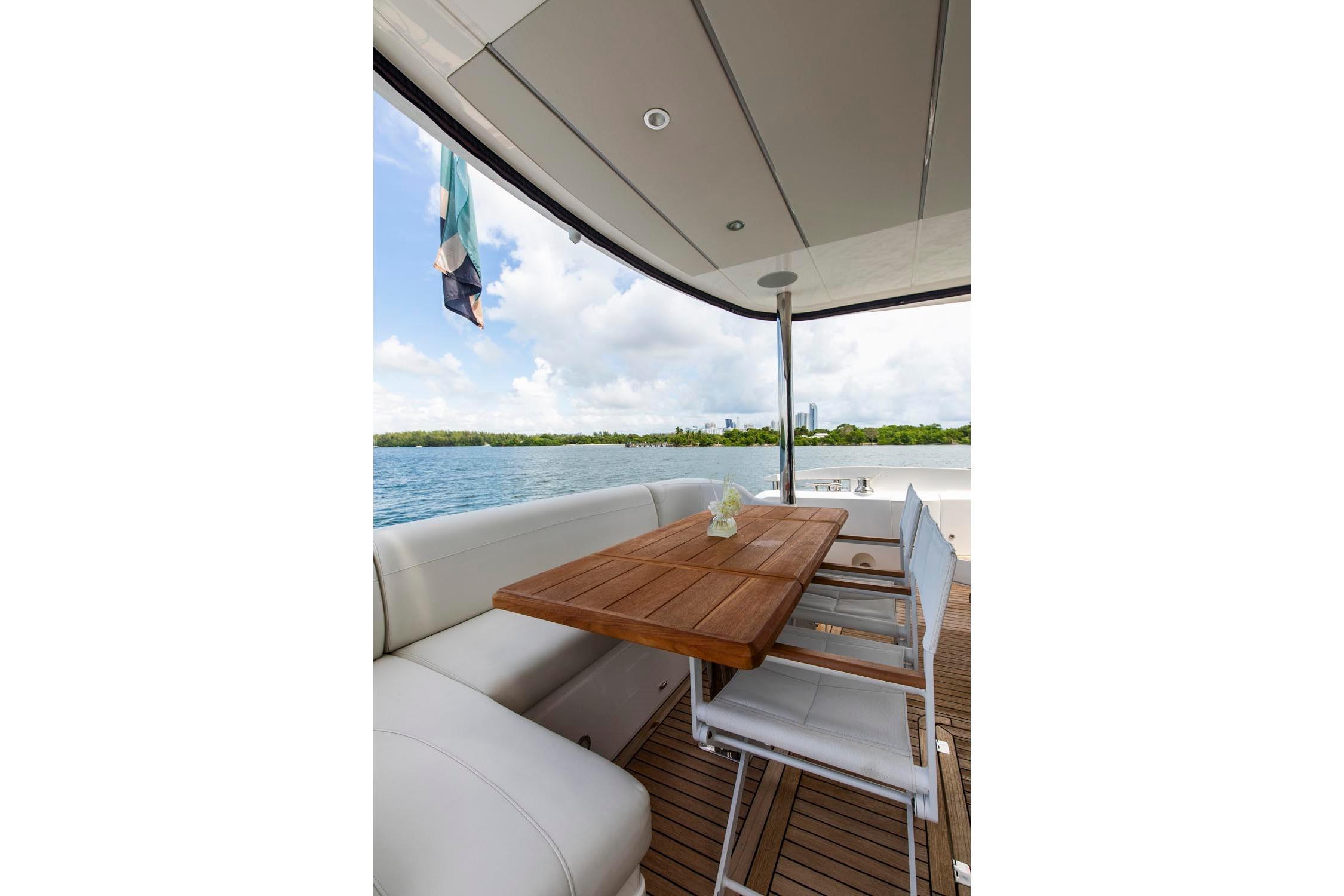 Luxurious Sunseeker Manhattan 68 yacht deck with seating and wooden table, 2021 model.