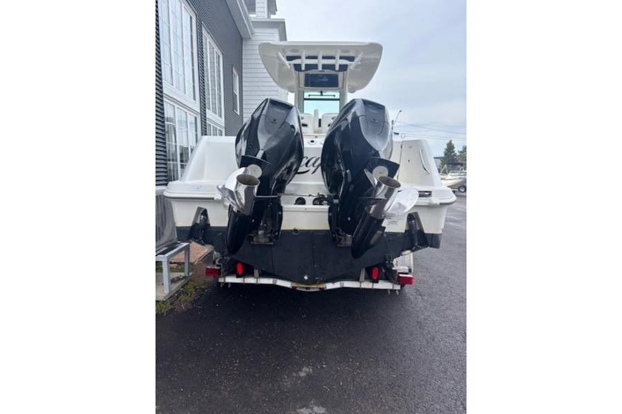 2015 Boston Whaler 250 Outrage boat with dual outboard motors, parked on wet pavement.