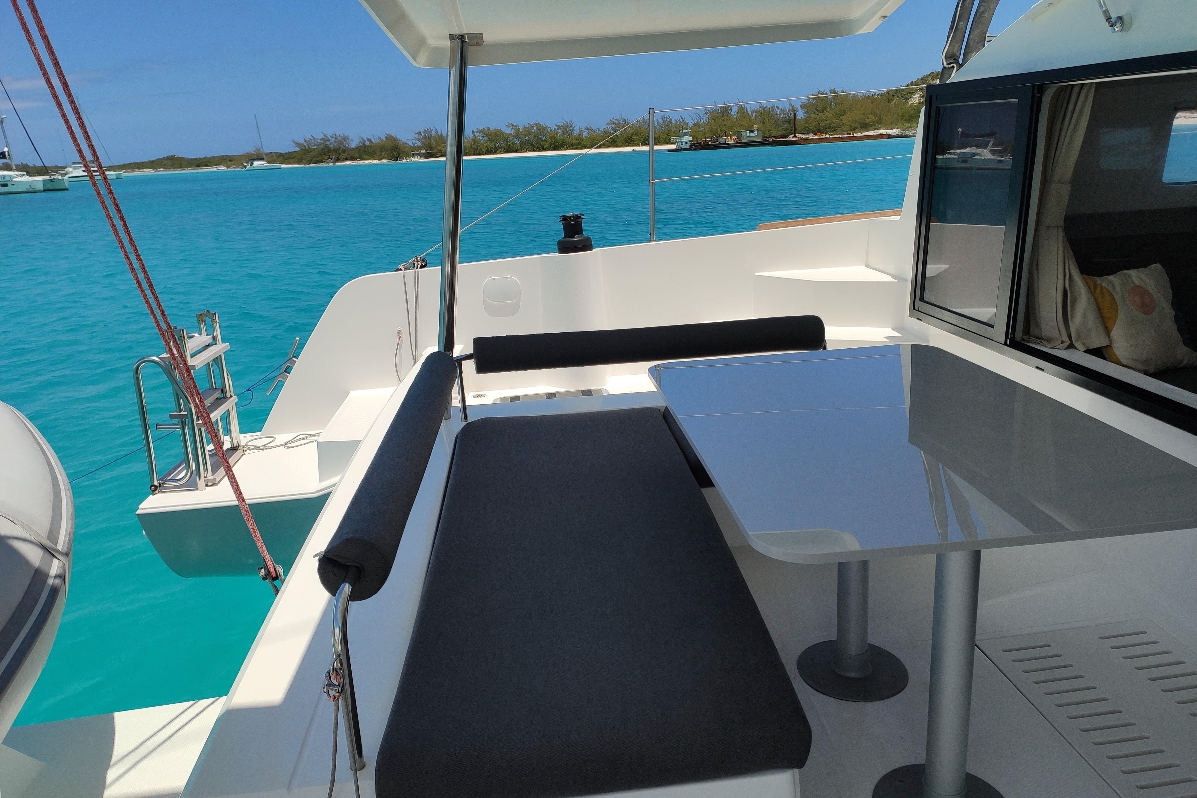 Modern NEEL 43 trimaran deck with seating, table, and stunning turquoise water view, 2022 model.