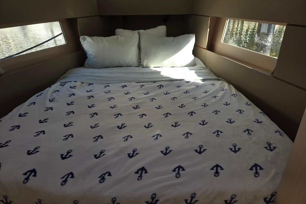 Cozy cabin interior of 2023 Beneteau Oceanis 38.1 with anchor-patterned bedding.