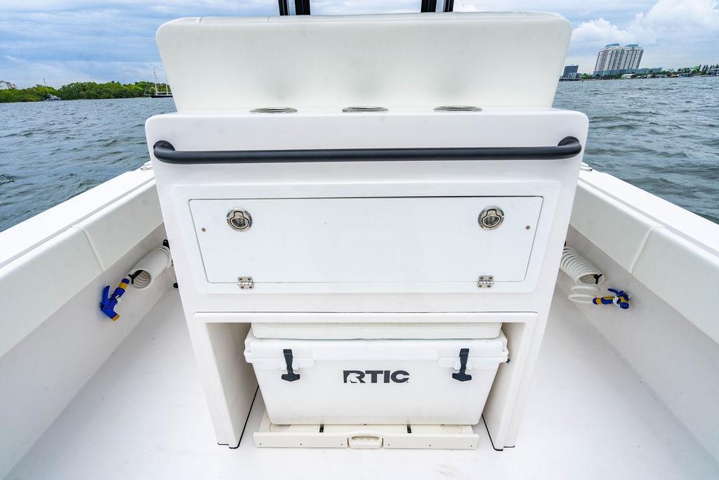 Reef Runner 280 boat interior with storage and cooler, 2027 model, on a scenic waterway.