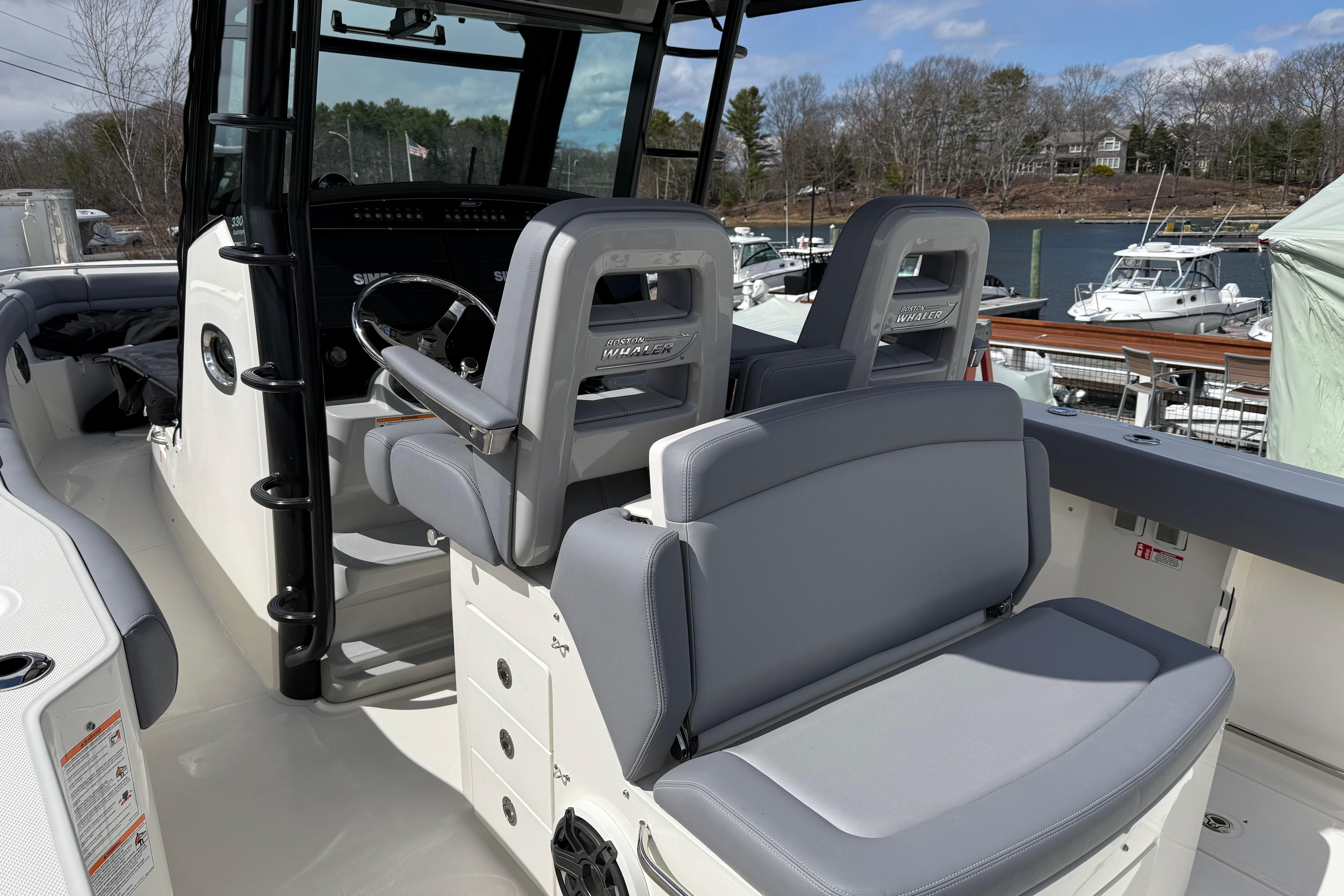 2026 Boston Whaler 330 Outrage boat interior with helm and seating, docked at marina.