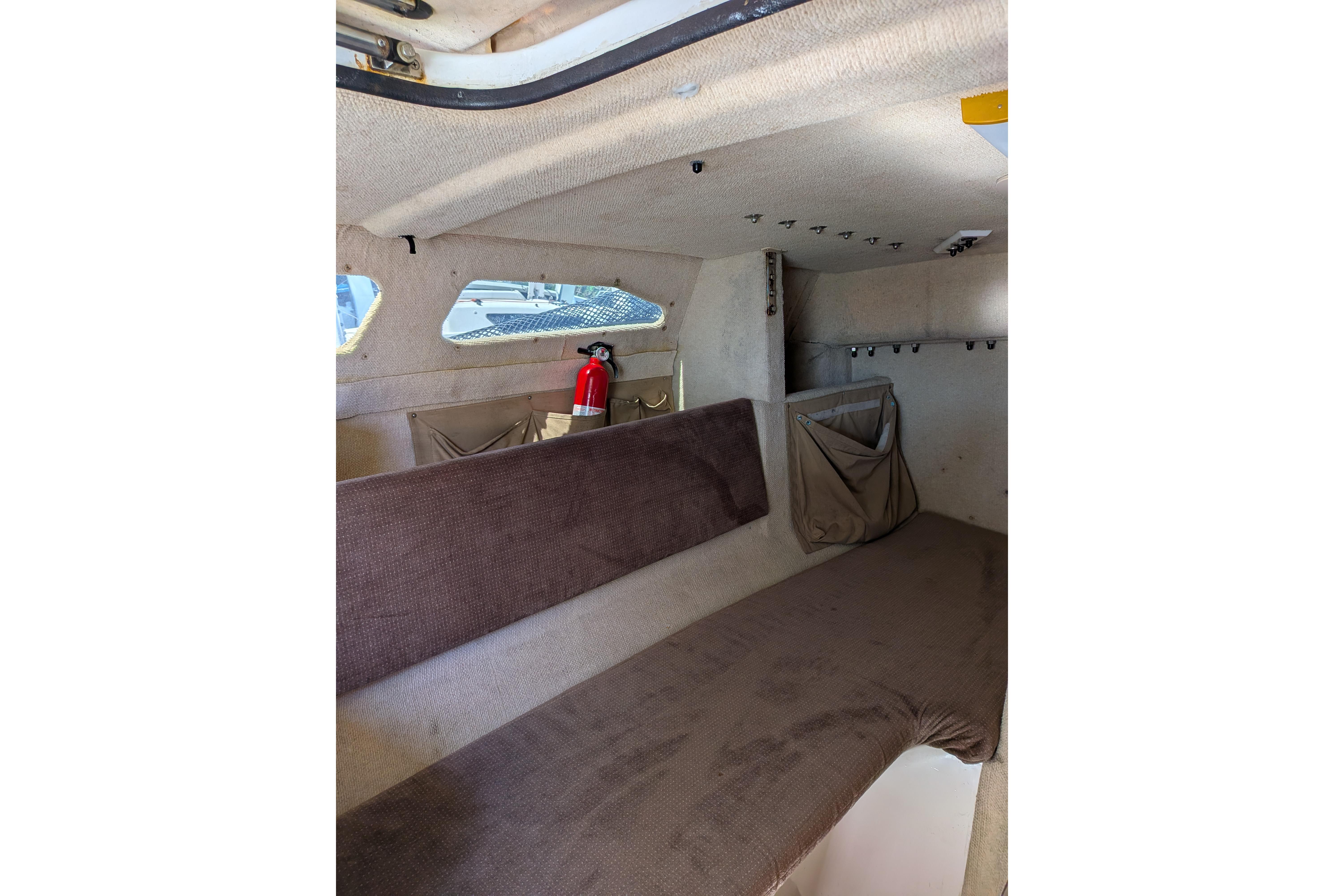 Interior of a 1991 Corsair F-27 sailboat cabin with seating and a fire extinguisher.