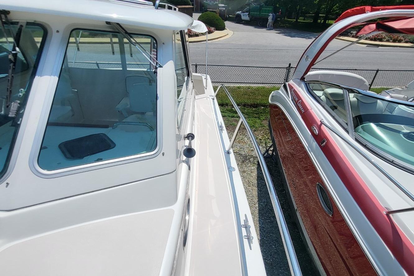 2006 Back Cove 29 boat docked beside a red vessel, showcasing sleek design and windows.