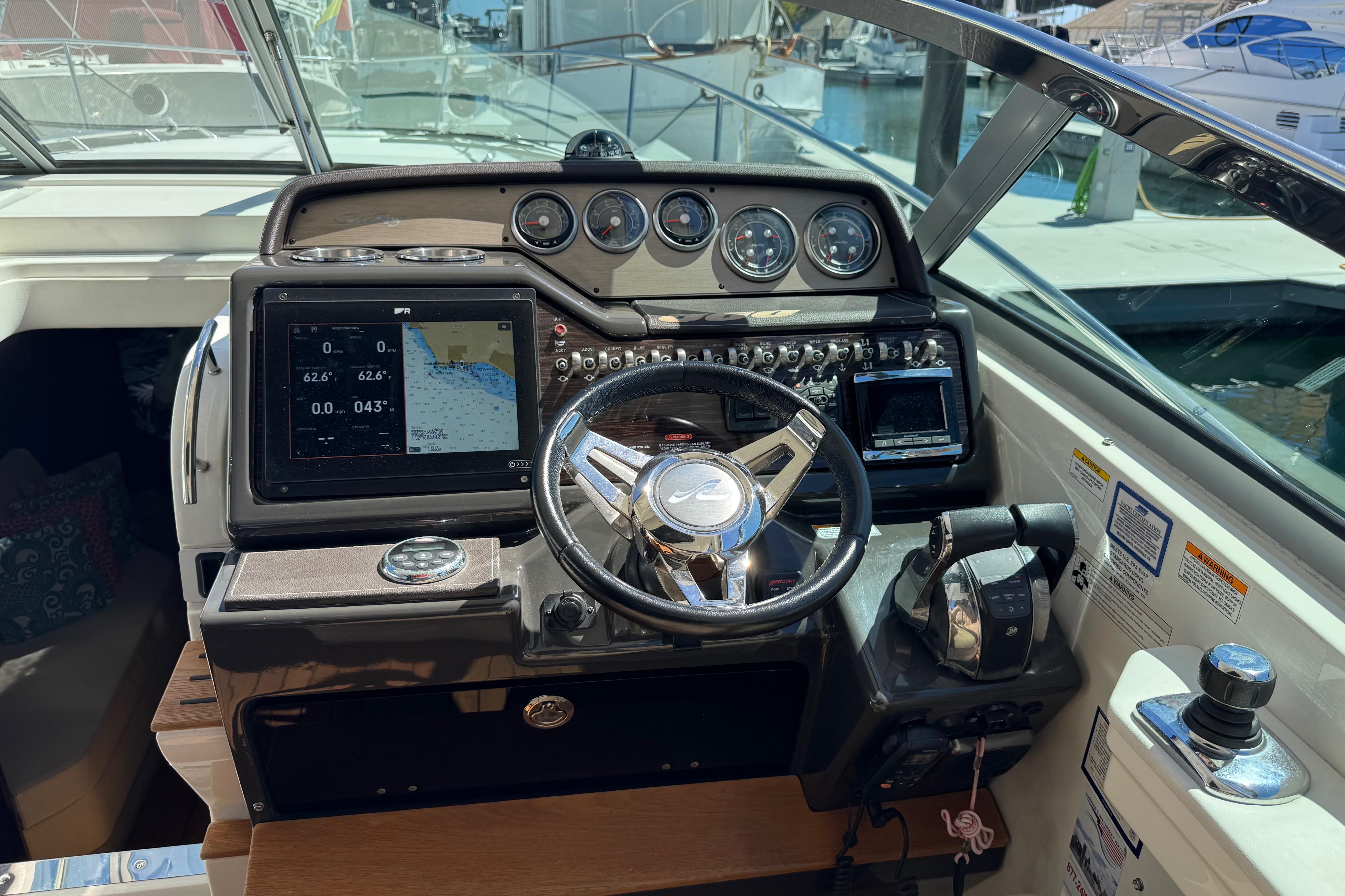 2016 Sea Ray Sundancer 350 helm with navigation display and controls in marina setting.
