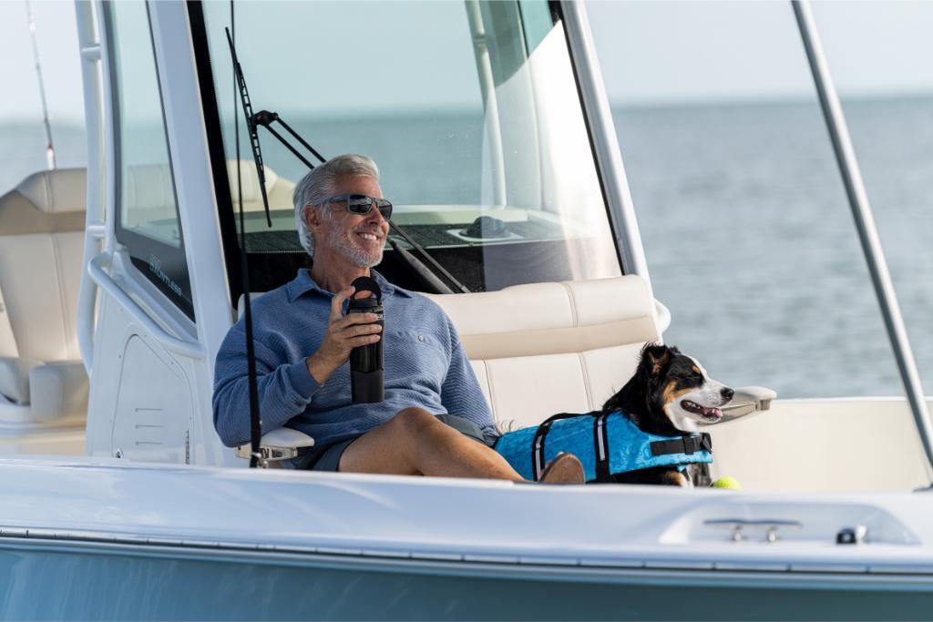 Man and dog relaxing on a 2024 Boston Whaler 280 Dauntless boat.