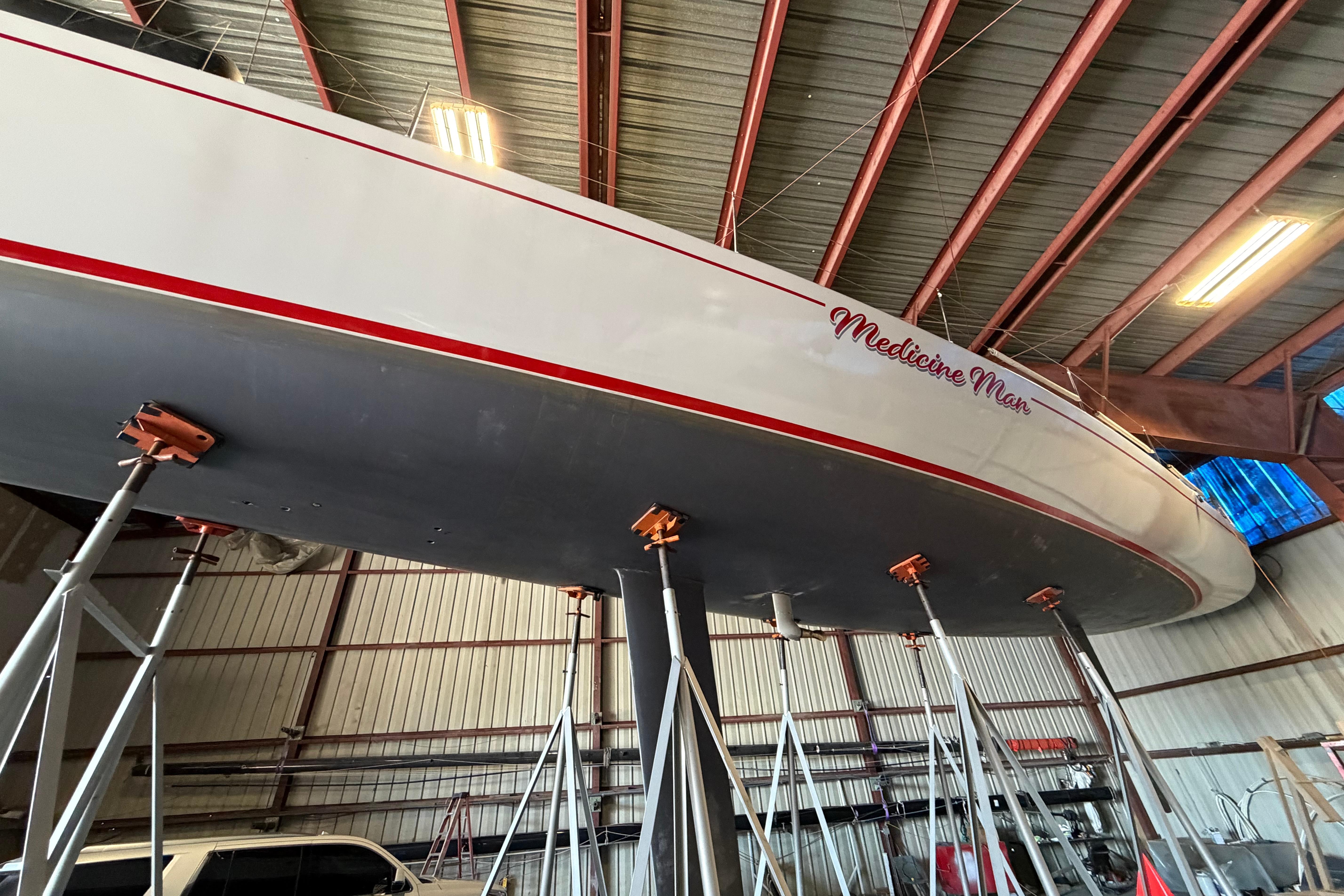 Andrews 63 sailboat "Medicine Man" in a boatyard, supported by stands, under a metal roof.