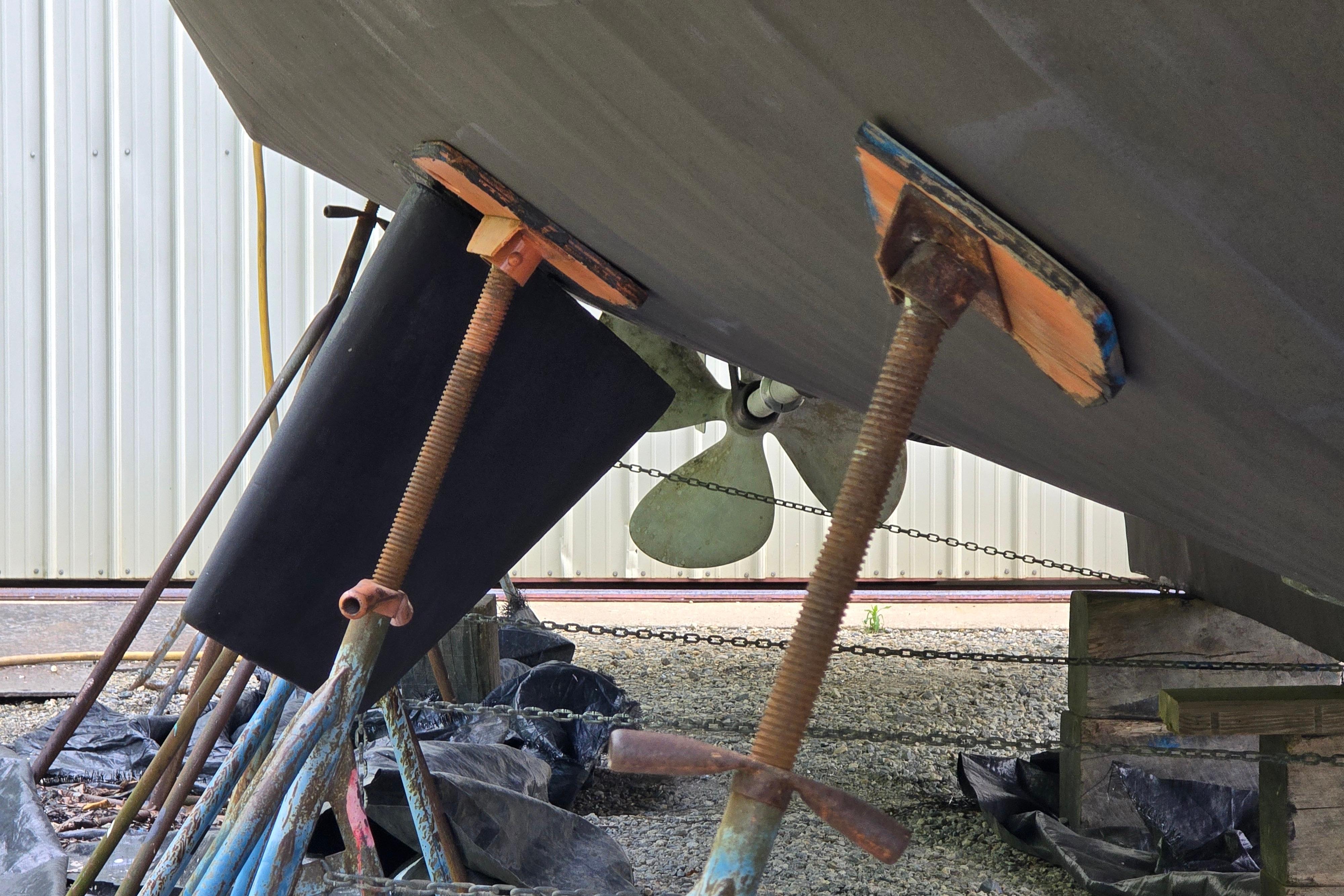 Bottom view of a 1980 Hatteras 70 Motor Yacht on supports, showing propeller and rudder.
